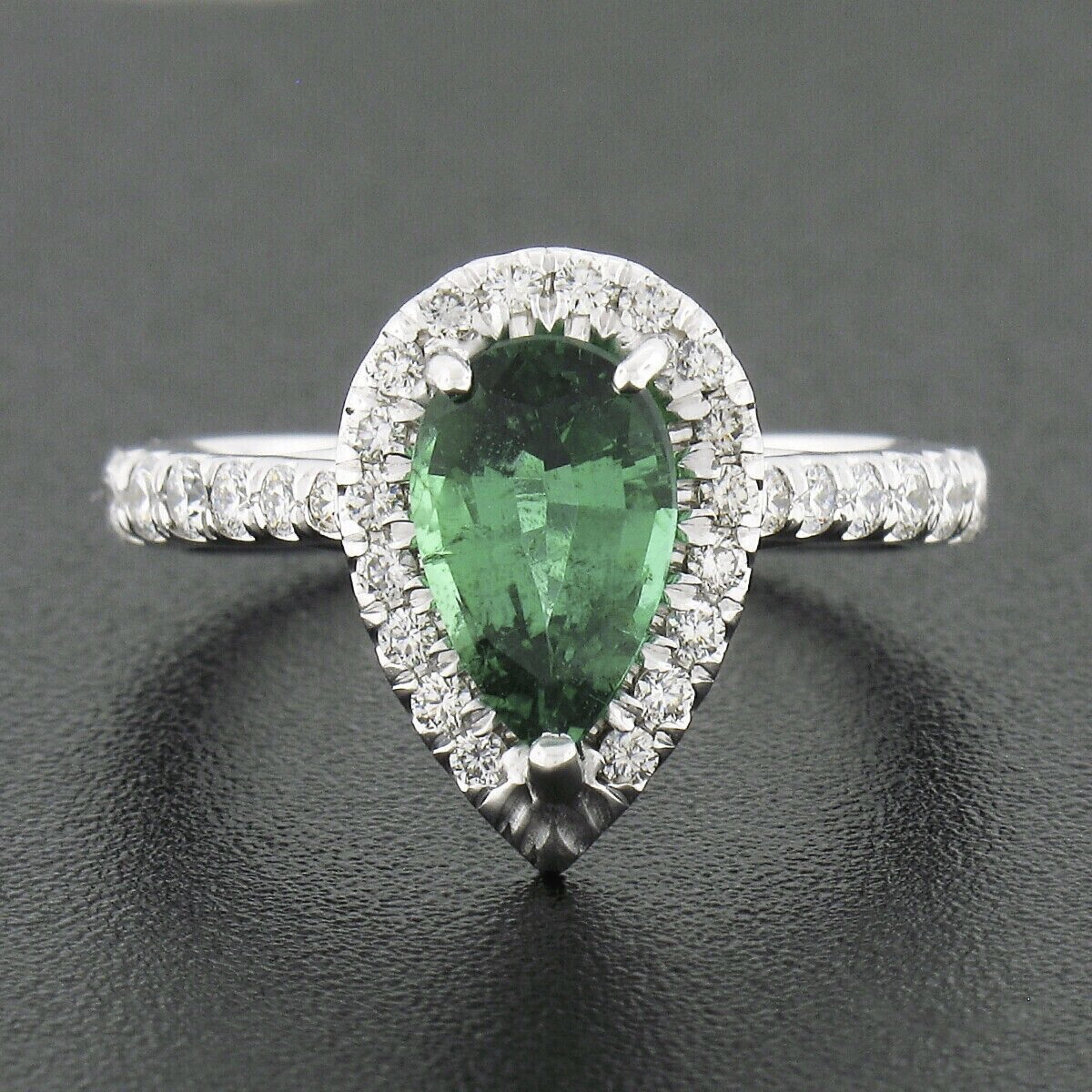 Up for sale is a truly gorgeous emerald and diamond engagement ring crafted in solid 18k white gold and features a breathtaking, 100% natural, pear brilliant cut emerald stone that displays the finest and most desirable vivid green color. This very