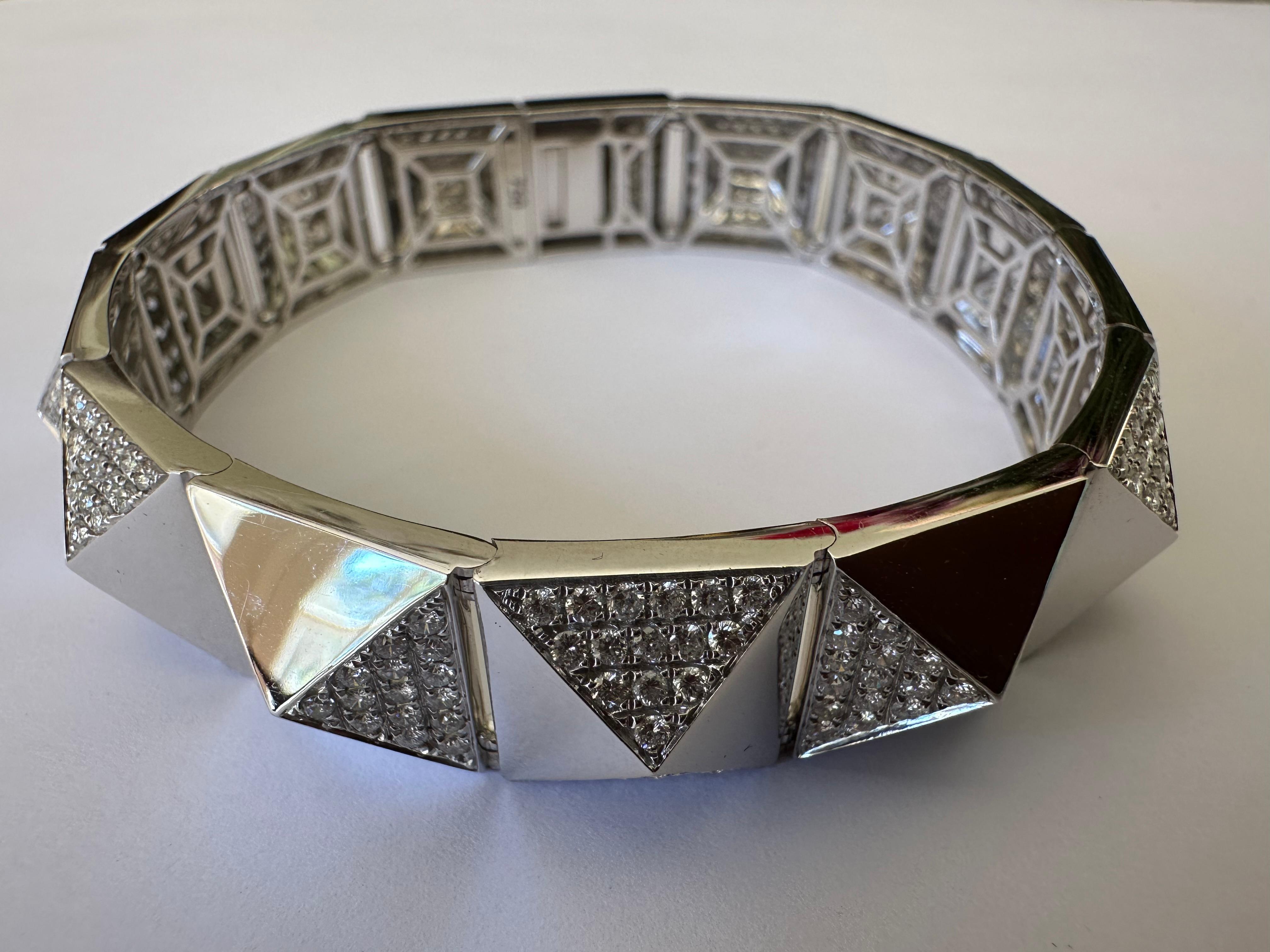 This bold, geometric Estate bracelet features pave-set round brilliant-cut diamonds together weighing approximately 4.55 carats, GH color VS-SI clarity, elegantly arranged on contrasting sides of stylized pyramid-shaped links crafted in gleaming 18K