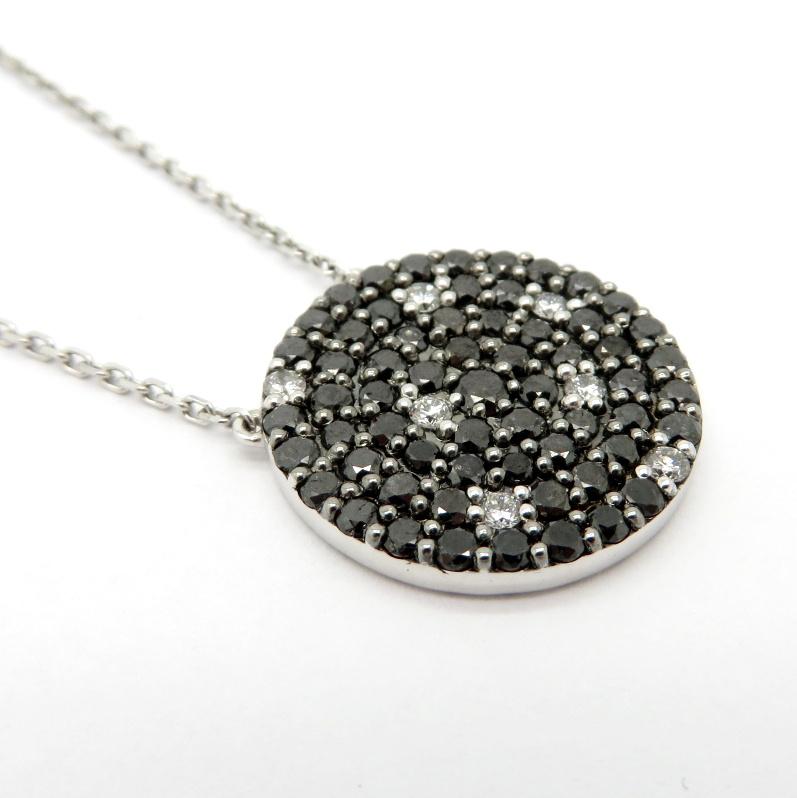 Estate 18K white gold black and white diamond pave circle pendant necklace. Showcasing 62 pave set round brilliant cut black diamonds weighing approximately 1.57 carats. Accented with seven round brilliant cut white diamonds weighing approximately