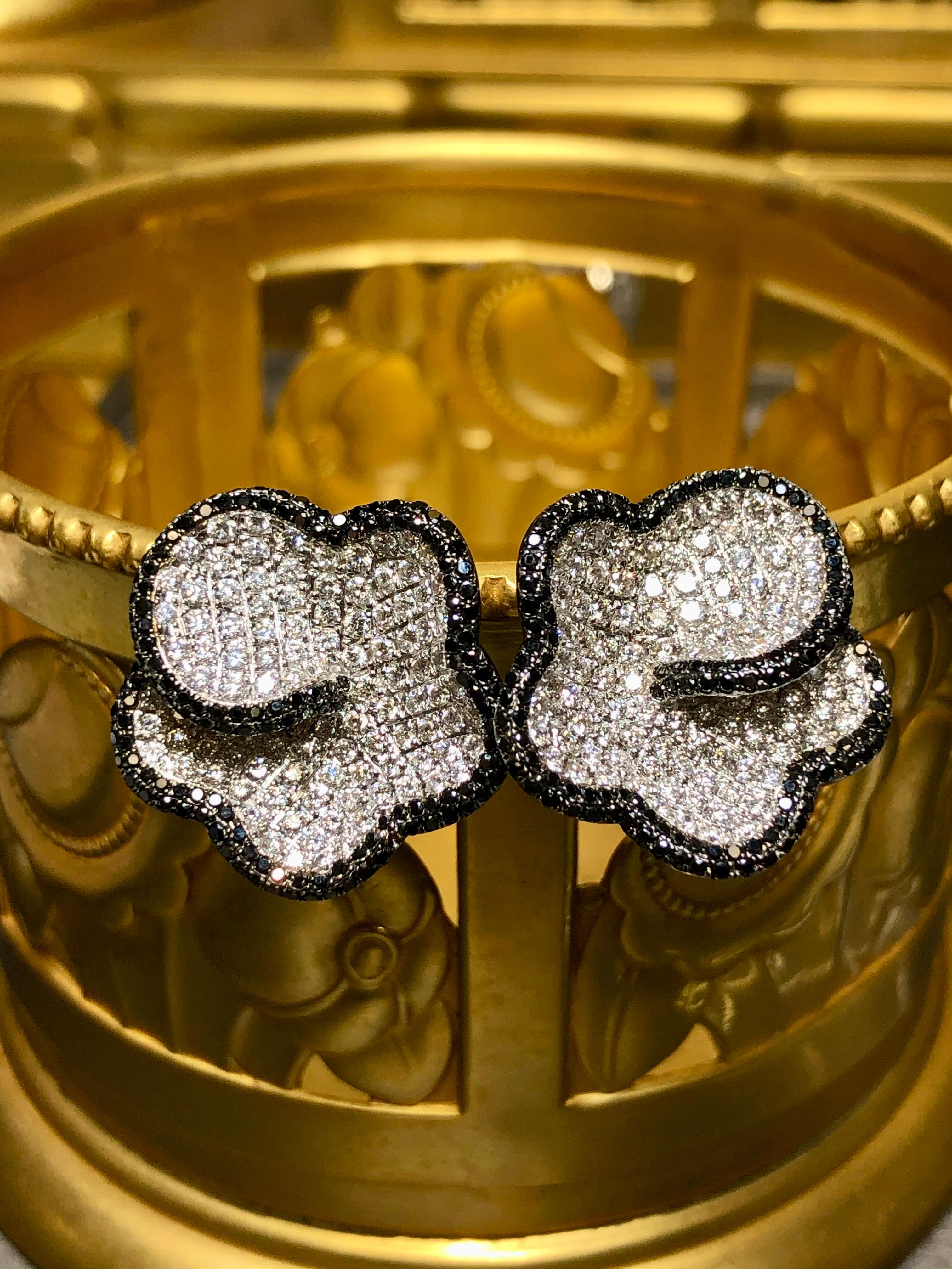 An elegant pair of nicely made contemporary huggie earrings done in 18K white gold set with approximately 3.45cttw in nicely matched G-H color Vs1-2 clarity round diamonds as well as 1.55cttw in natural black diamonds. These earrings have posts with