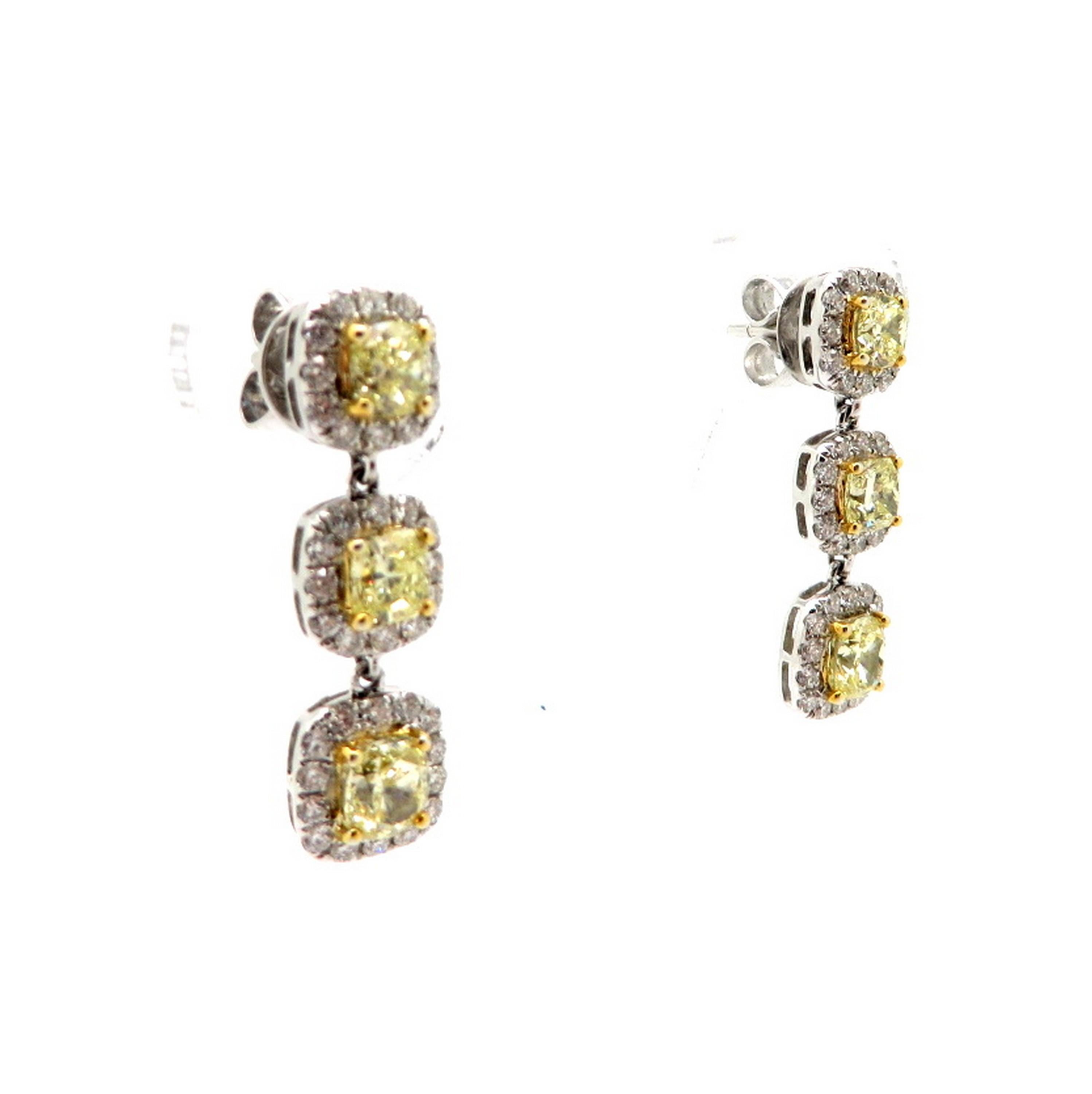 Estate 18K white gold fancy yellow cushion diamond dangle halo earrings. Showcasing six fancy yellow cushion brilliant cut diamonds each four prong set, having VS1 clarity grade, and weighing a combined total of 2.38 carats. Accented with 76 round