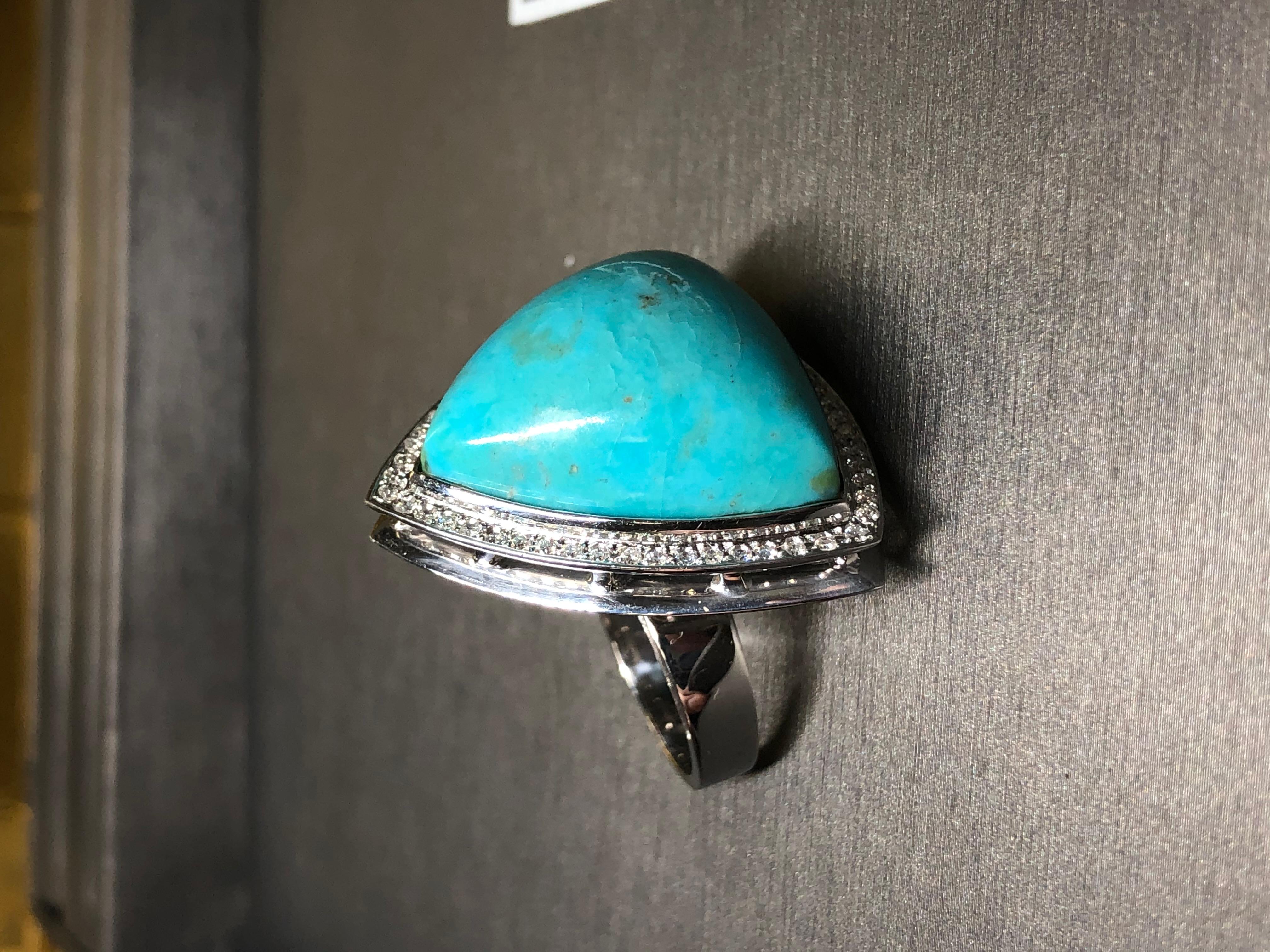 Amiamo i gioielli che non hanno scuse e questo anello non fa eccezione. Realizzato in oro bianco 18 carati, questo anello ha al centro un grande triangolo di turchese cabochon circondato da circa 0,53 carati di diamanti rotondi di colore G-H e