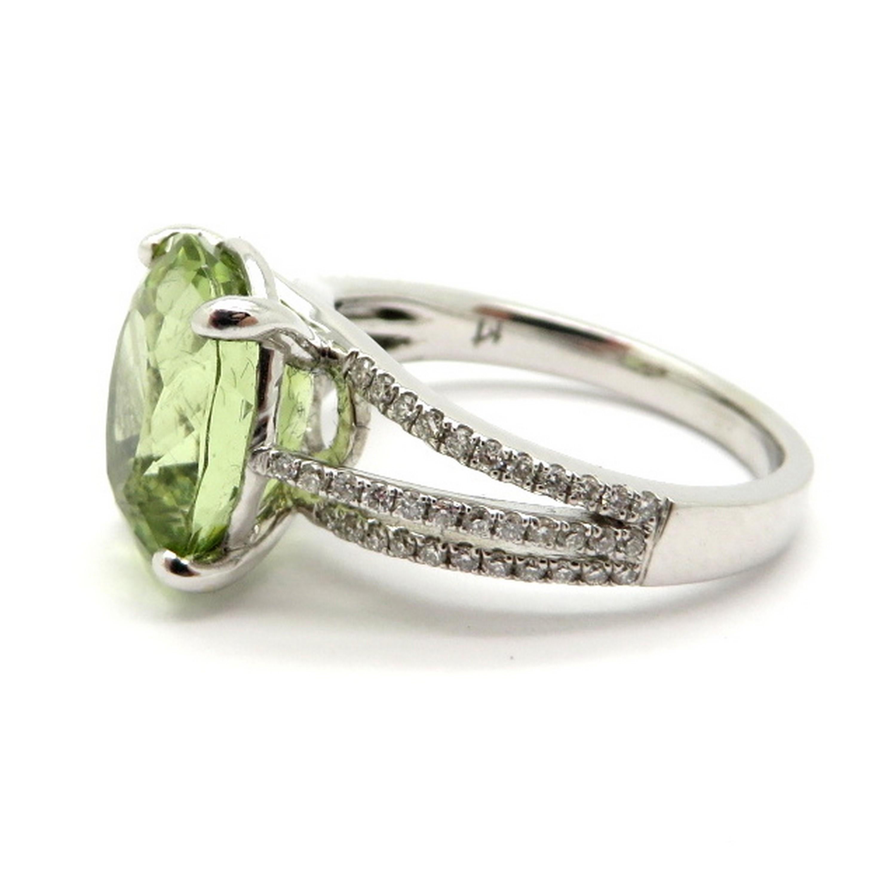 Estate 18K white gold light green beryl and diamond fashion ring. Showcasing one oval brilliant cut light green beryl, four prong set, weighing approximately 4.05 carats. Accented with 68 round brilliant cut diamonds, bead set, weighing