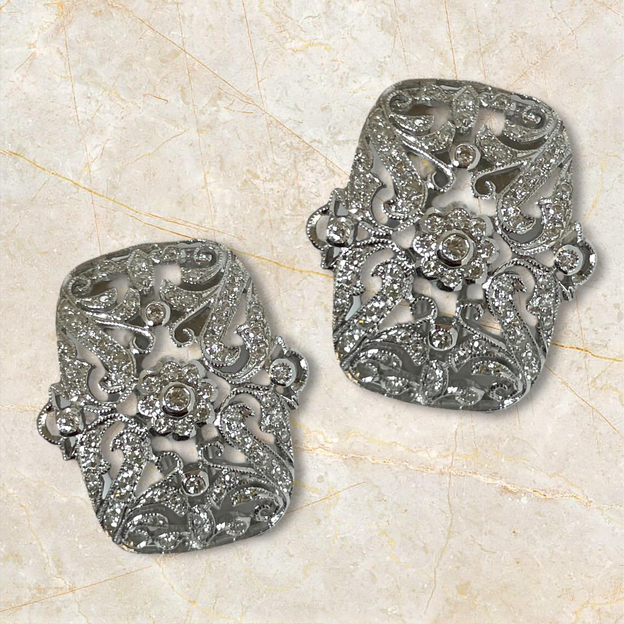 Réalisées en or blanc 18 carats, ces boucles d'oreilles de collection présentent un motif de volutes captivant avec des accents de milgrain, magnifiquement complété par des diamants scintillants. Les détails complexes et les dos en oméga créent un
