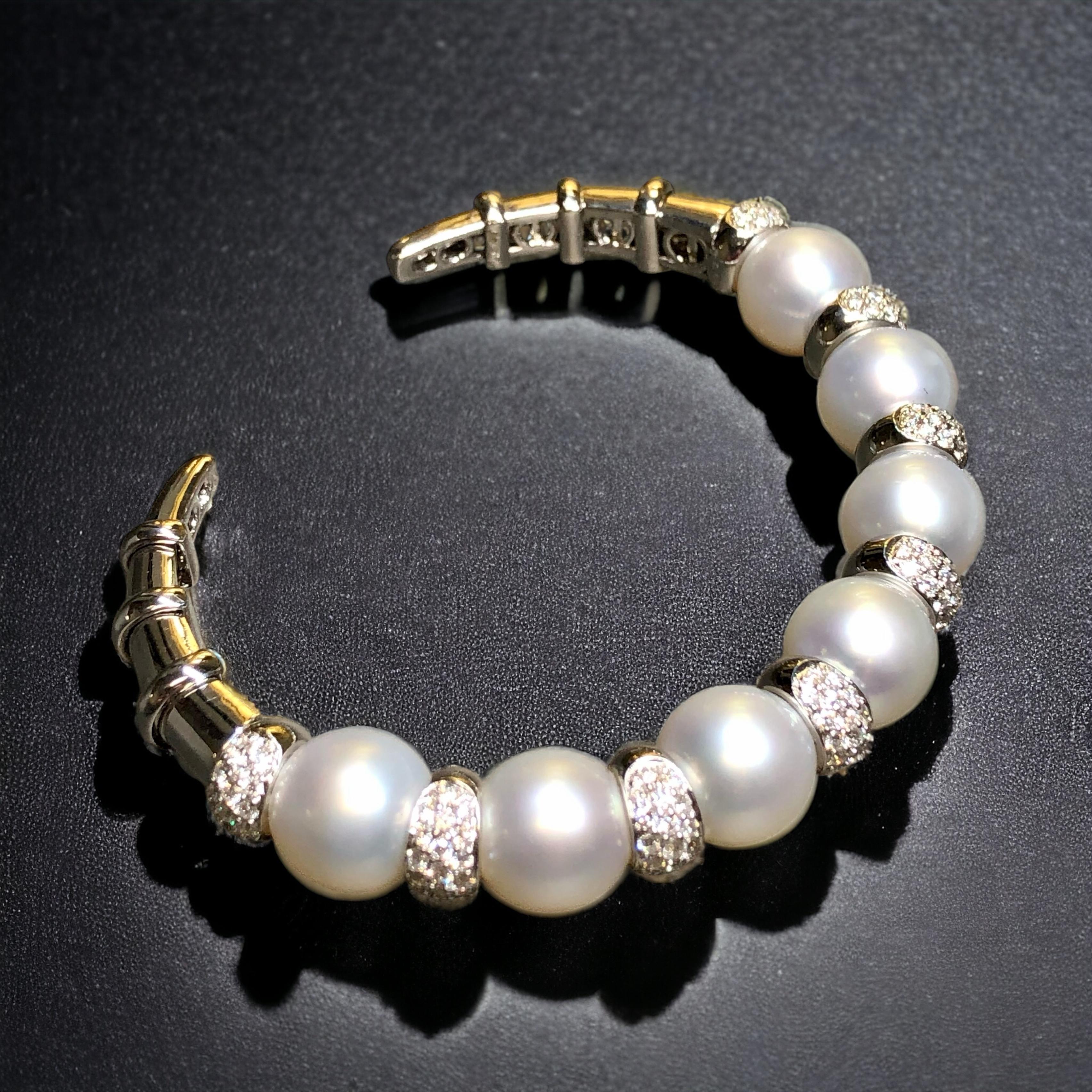 An exceptionally well-made cuff bracelet crafted in heavy 18K white gold and flush set with approximately 2.40cttw in F-H color Vs1-2 clarity round diamonds with each section being separated by a natural South Sea pearl ranging 10.5mm by