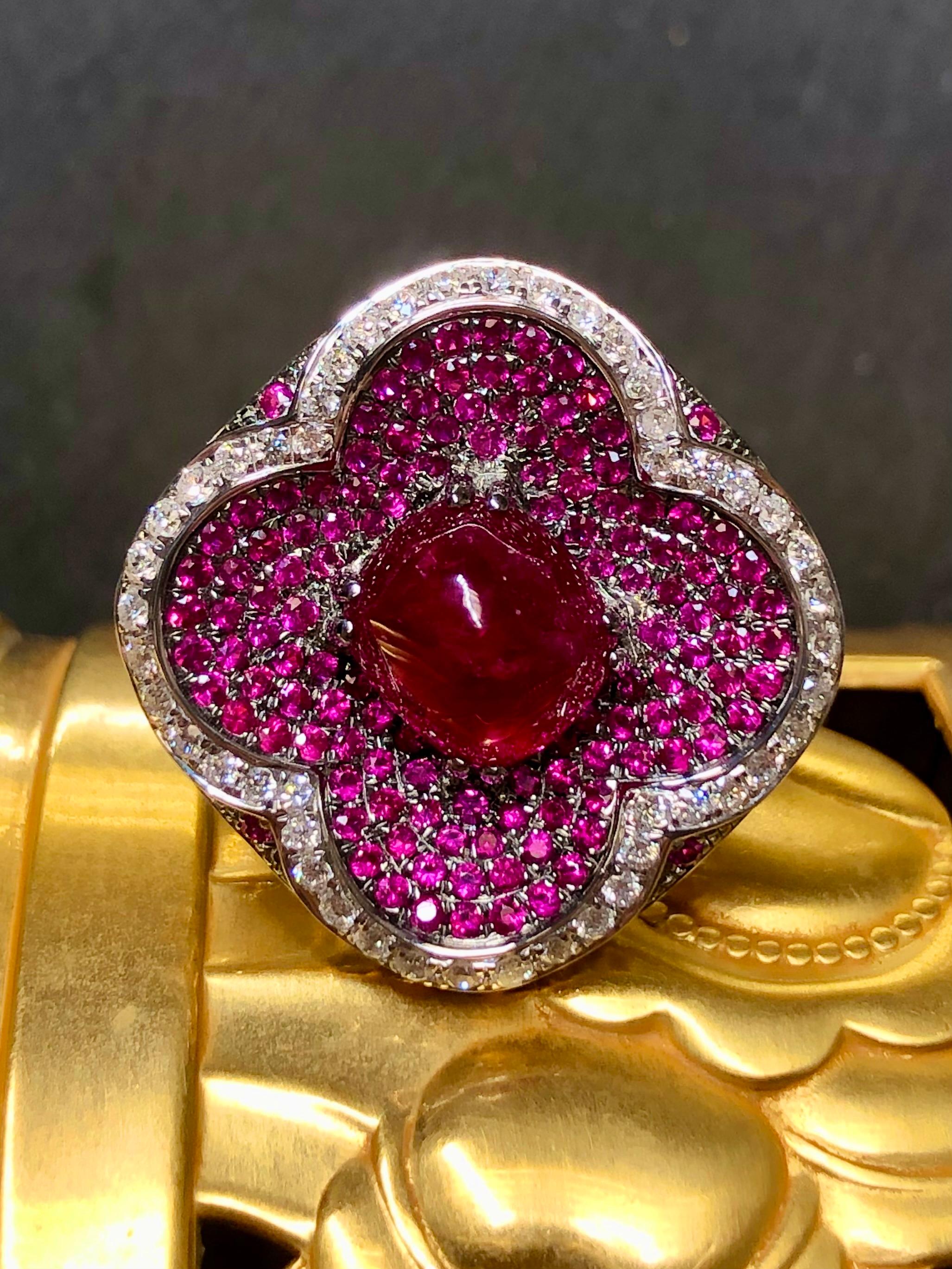 A contemporary gemstone cocktail ring crafted in 18K white gold centered by a 1.03ct natural cabochon sugarloaf cut vividly red ruby (heat only) surrounded by another 4.65cttw in natural rubies as well as 1.23cttw in G-I color Vs1-Si1 clarity round