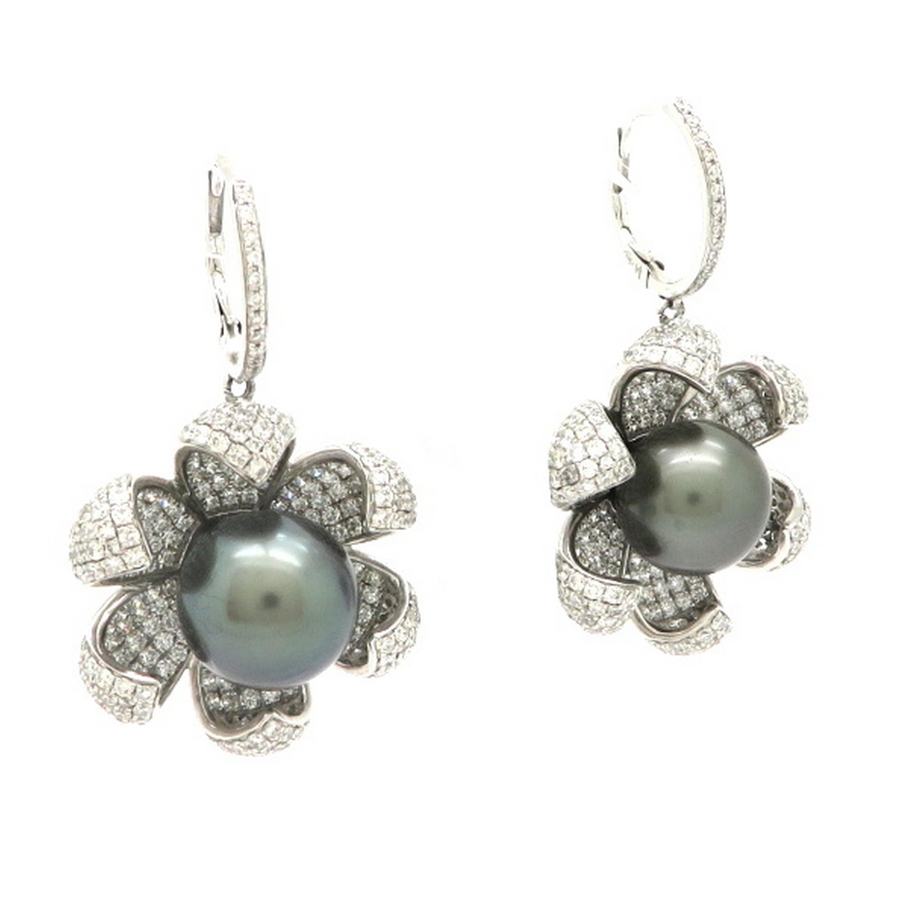 Estate 18K white gold Tahitian Pearl and pave diamond flower dangle earrings. Showcasing two Tahitian round black pearls, each measuring 12 mm. Accented with 586 round brilliant cut pave set diamonds set in a floral motif. The dangle earrings are