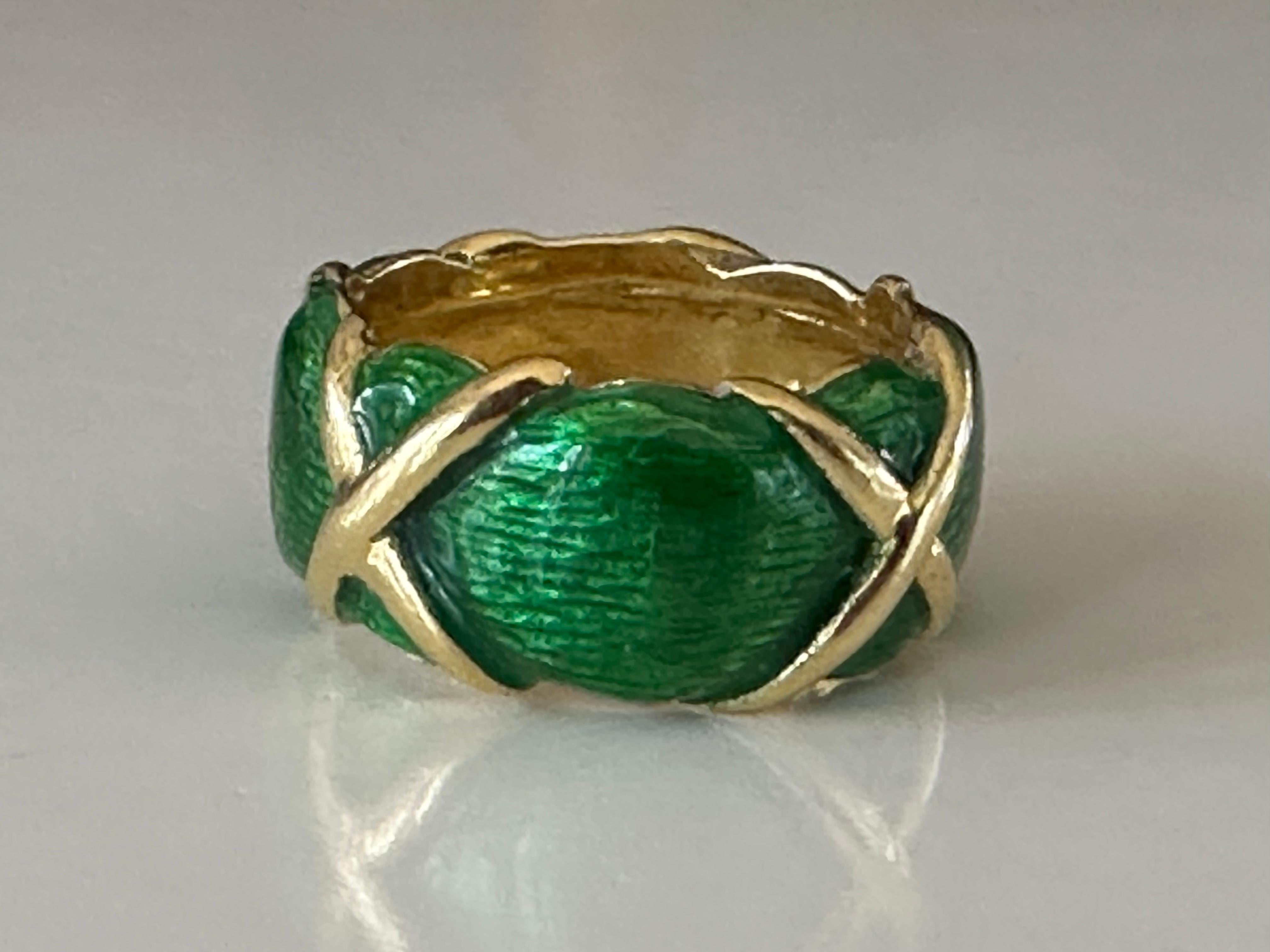 Crafted in the 1960s, this stunning Estate band features vibrant emerald green enamel overlaid with a repeating X design in 18kt yellow gold. 
Size 5.25. 
