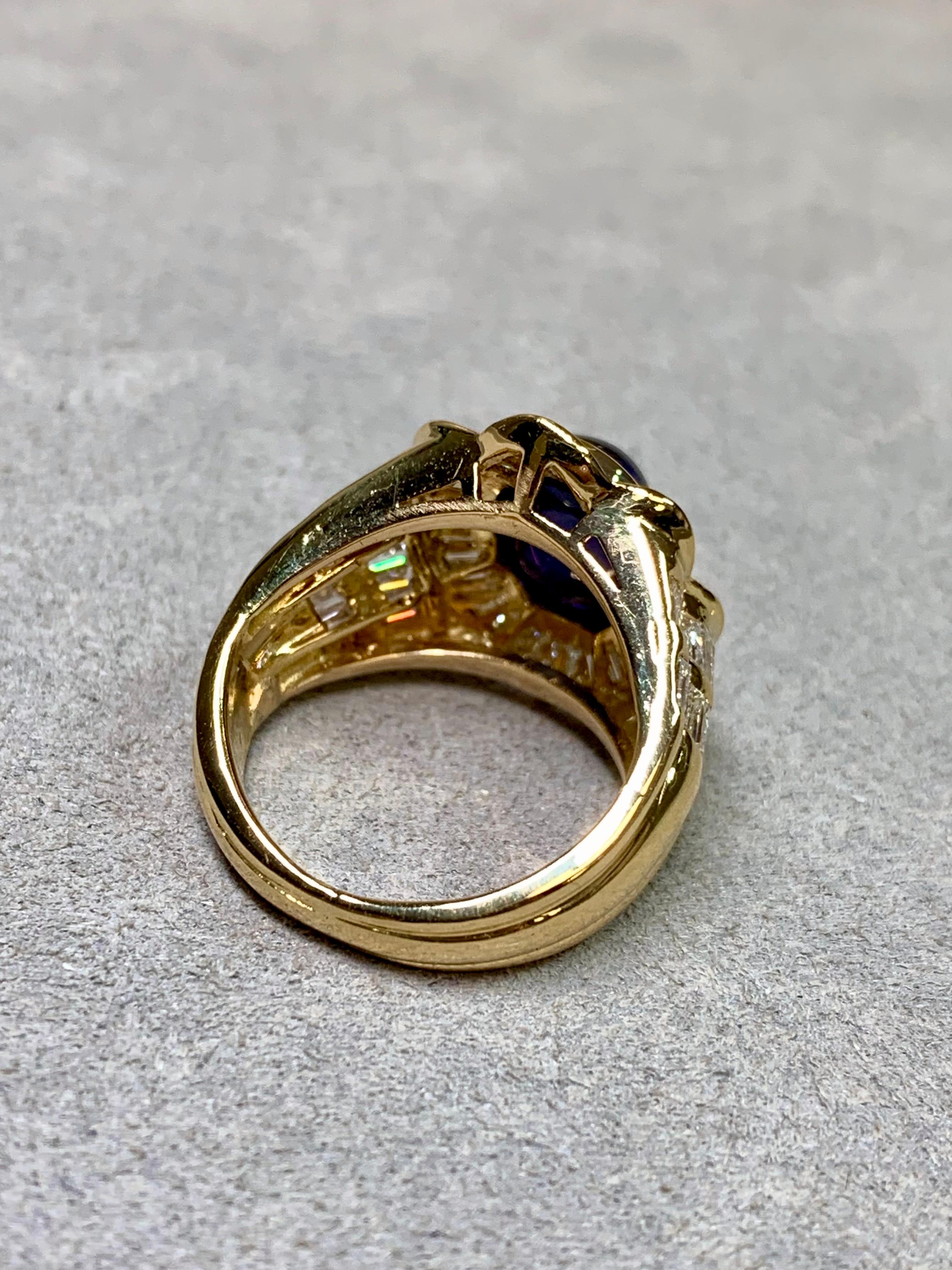 Une bague de succession d'une audace impressionnante, réalisée en or jaune 18 carats et centrée sur un saphir cabochon naturel d'un bleu profond pesant environ 5 carats. Des diamants baguette parfaitement assortis, de couleur G-I et de pureté Vs1-2,
