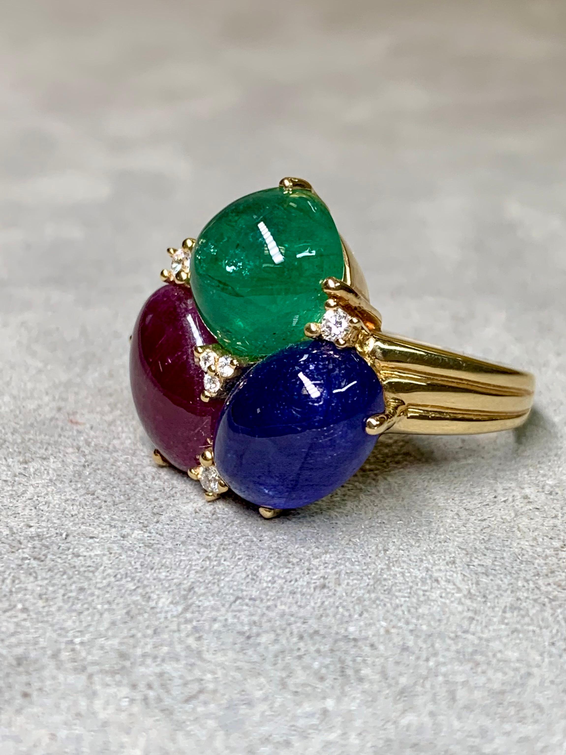 
An estate cocktail ring crafted in heavy 18K yellow gold, showcasing exceptional craftsmanship and solid construction. The design features three impressive prong-set cabochon gemstones arranged in a striking cluster — a vivid green emerald (approx.