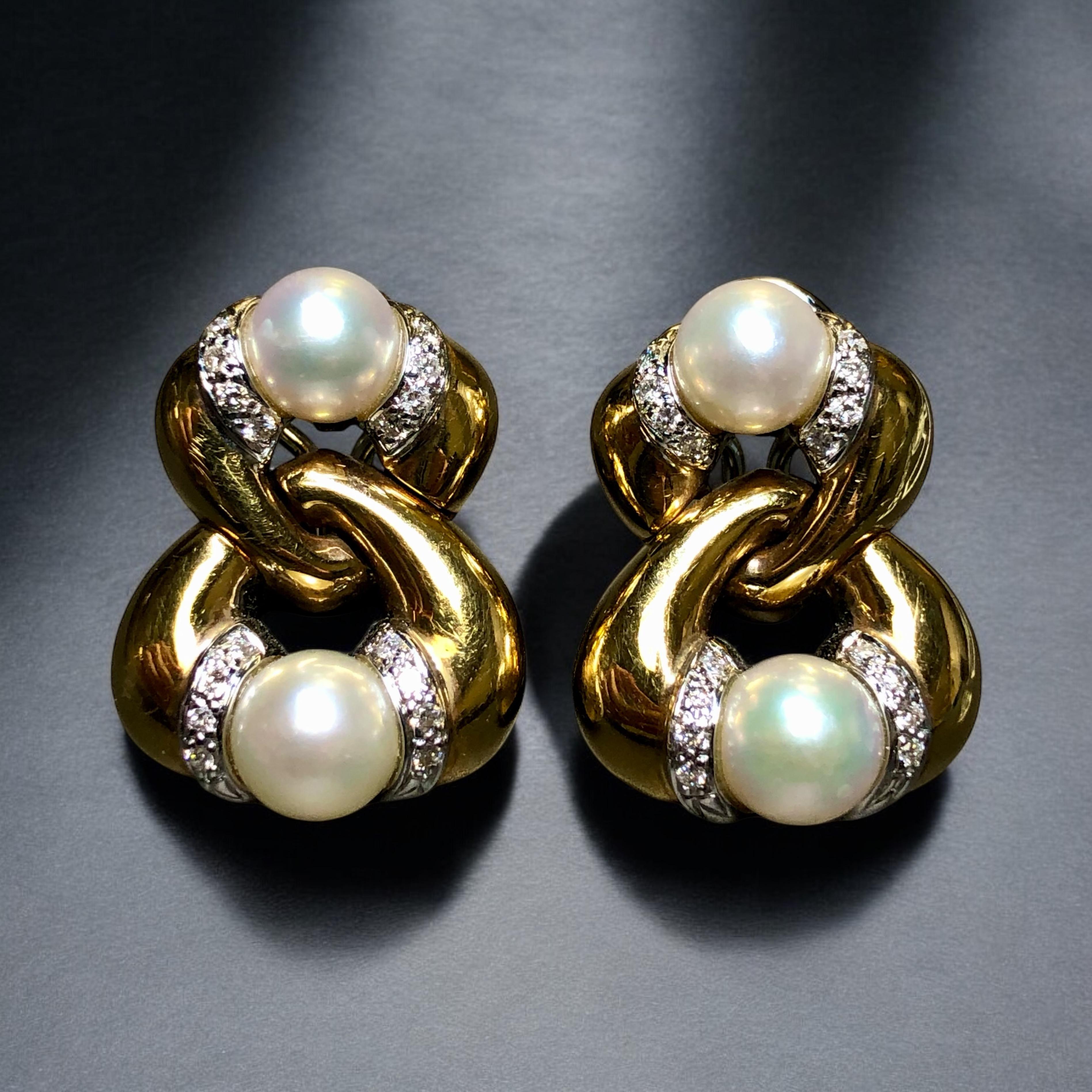 A beautifully designed pair of earrings with clean and bold curves done in 18K yellow gold set with approximately .64cttw in H-I color Si1-2 clarity round diamonds and finished with 7.30mm to 8mm cultured pearls. These earrings have posts with omega