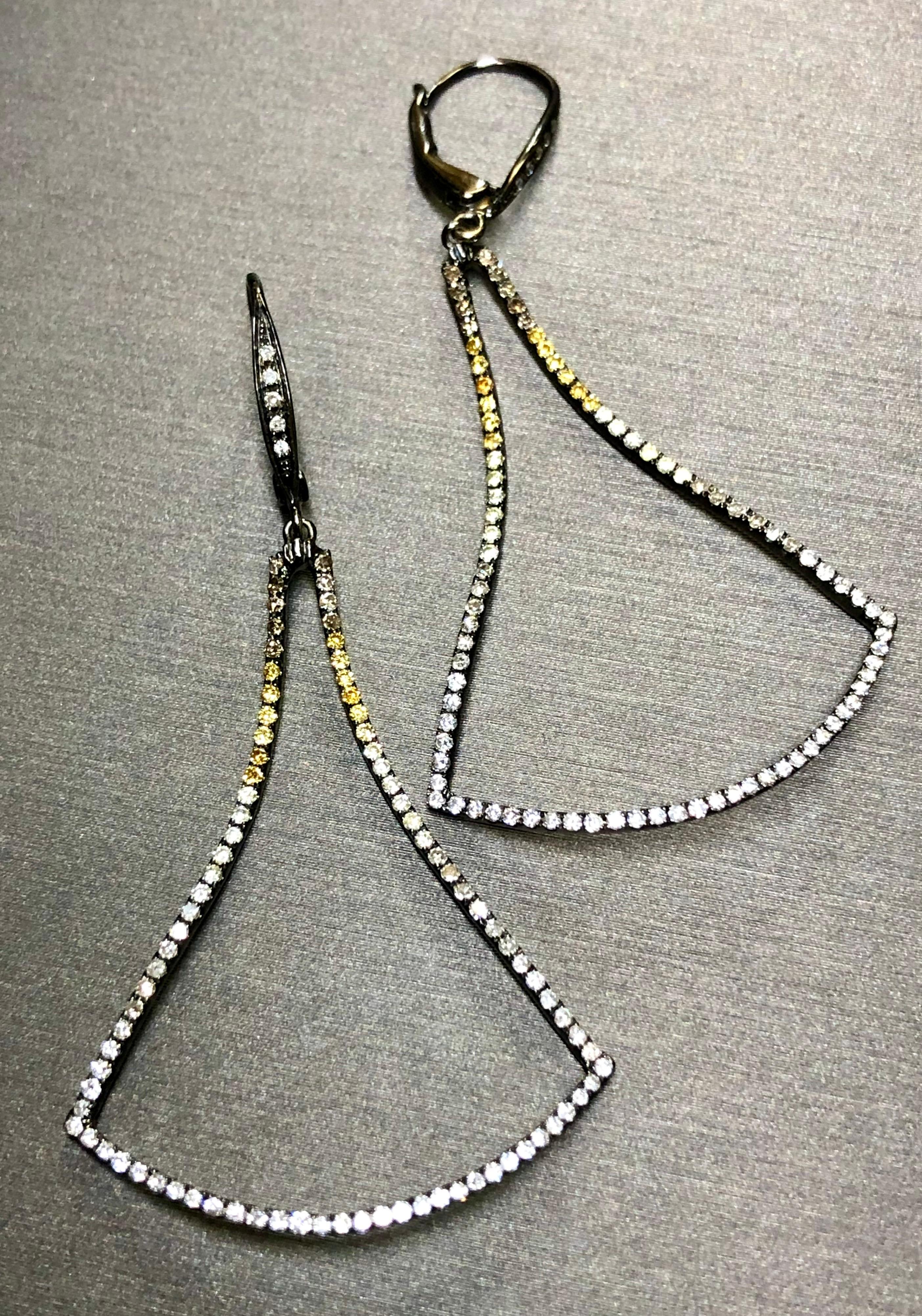 A contemporary pair of earrings done in 18K white gold and finished in black rhodium set with 180 round diamonds ranging from G color white diamonds all the way through brown and yellow fancy color diamonds with all stones ranging Si1 to I1 in