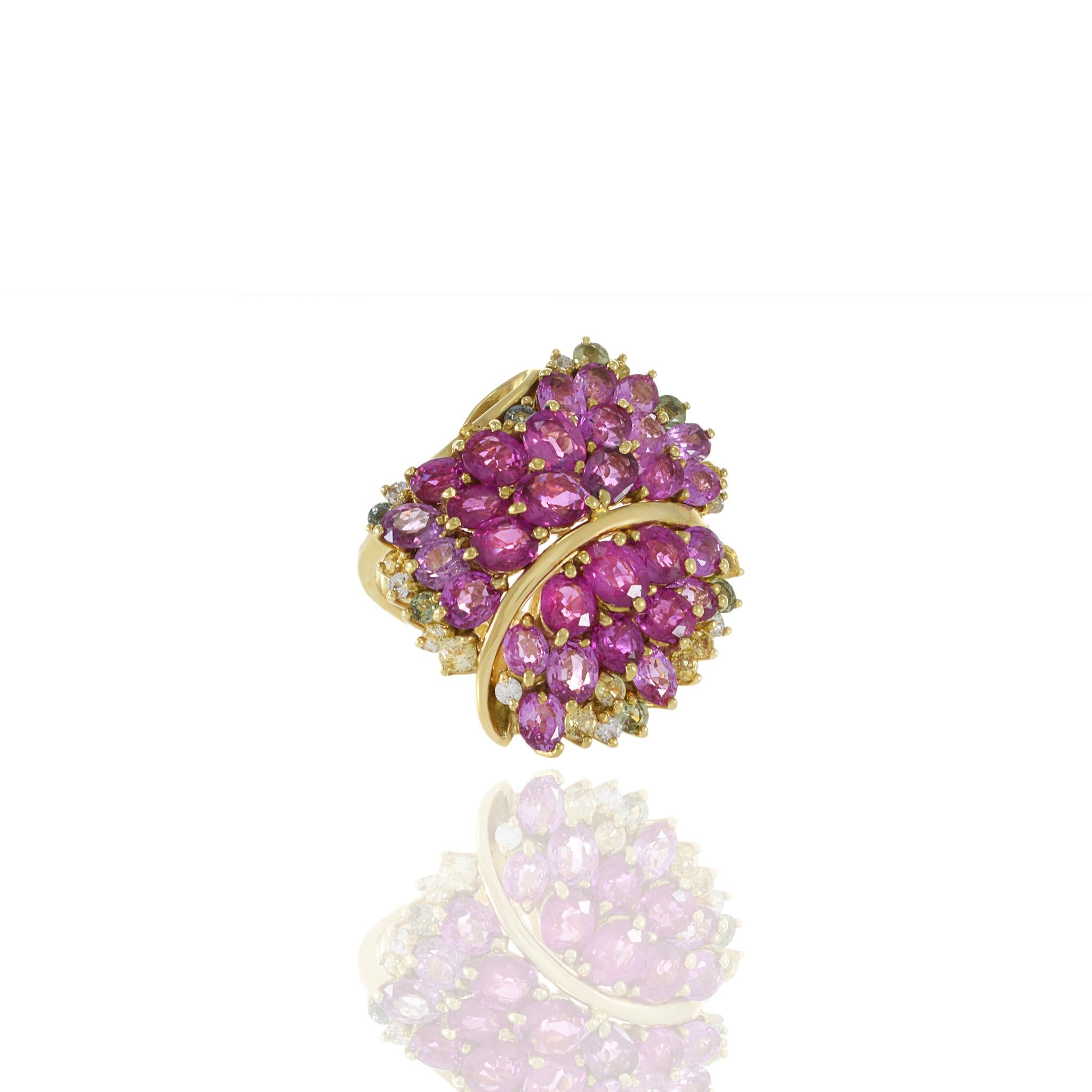The Estate 18KT Yellow Gold Pink/ Green Sapphire and Diamond Cluster Cocktail Ring is an embodiment of luxurious elegance and vibrant beauty. This magnificent ring showcases a breathtaking array of round cut genuine pink and green sapphires,