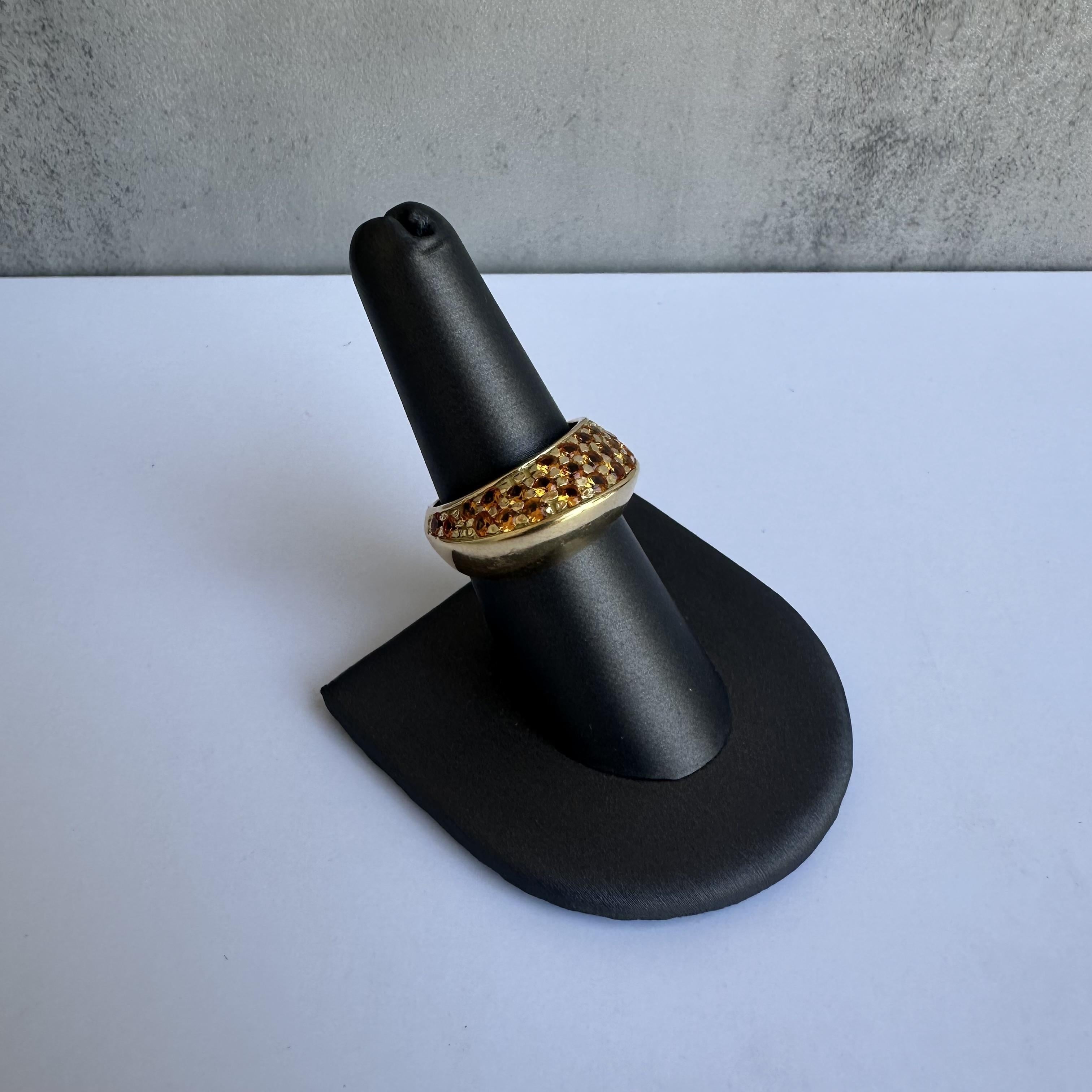 Discover the elegance of this Estate 18kt Yellow Gold Ring, featuring 27 vibrant orange gemstones, either citrine or orange sapphire, weighing approximately 1.6 carats. The ring showcases Italian craftsmanship, evidenced by the 