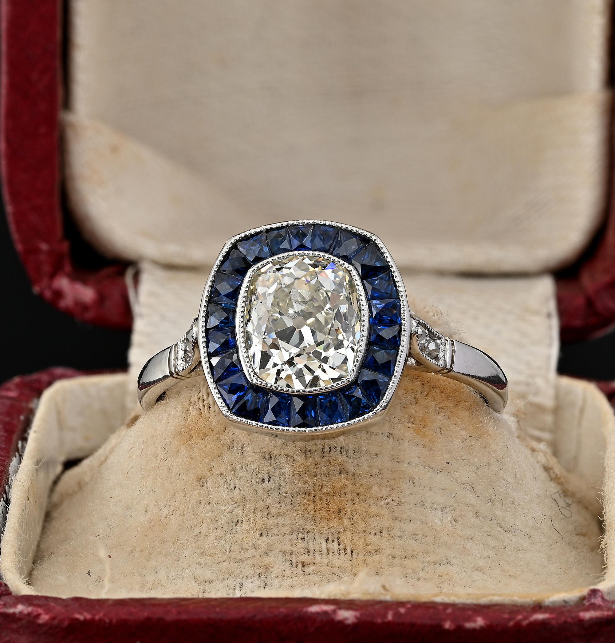 An estate Diamond and sapphire engagement ring featuring a 2.10 Ct  antique cushion cut – old mine cut Diamond-  I/J colour VVS clarity, littler old mine cut Diamonds chasing the shoulders adding . 08 Ct. Diamond is surrounded by a halo of French