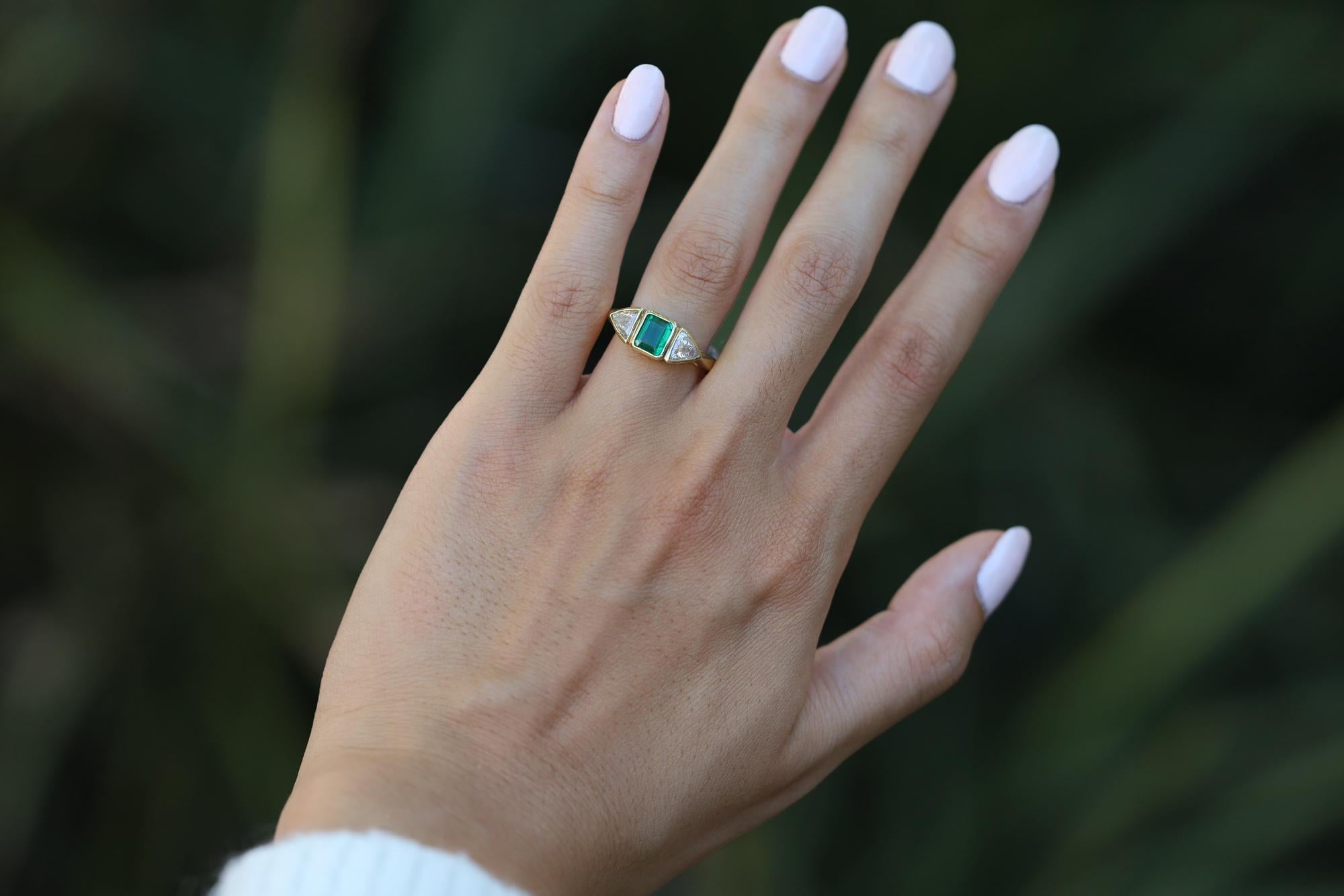 A stunning vintage estate engagement ring from the estate of Hollywood icon Robert Mitchum. Hand crafted with a timeless, early contemporary impression. The trinity centers on a natural emerald weighing 0.97 carats, a vivid green presenting