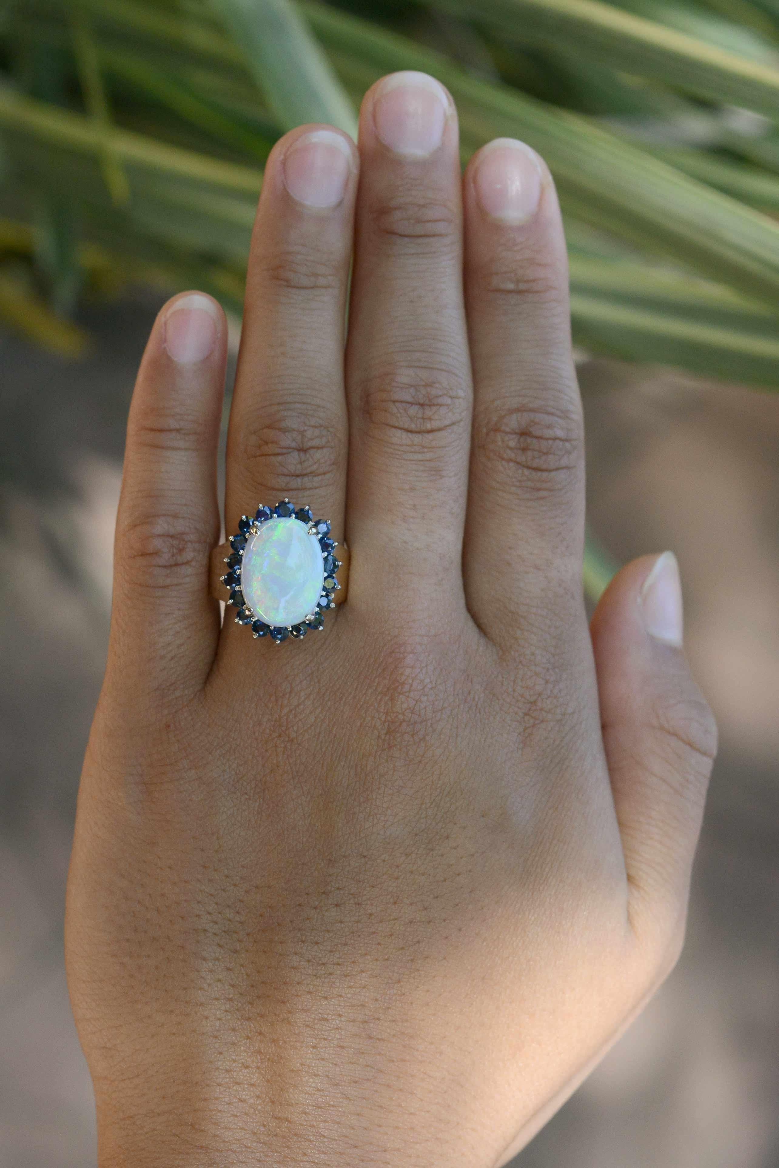 This ring is on hold for a customer.

A charismatic combination, this 5 carat Australian opal cocktail ring makes a bold statement. Featuring fiery flashes of blue-green, the gemstone smartly surrounded by velvety blue sapphires and supported by a