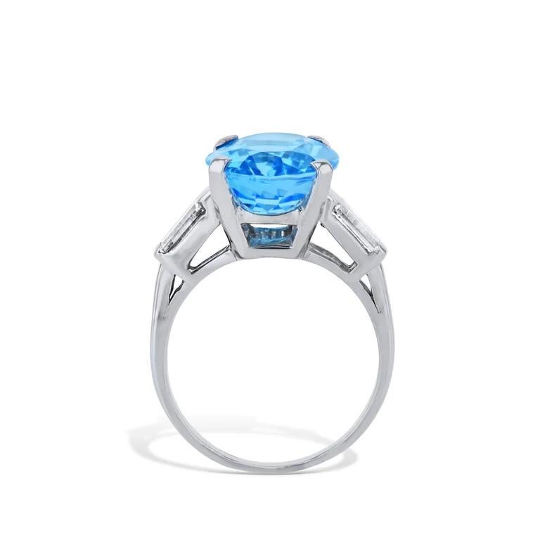 This stunning swiss blue oval topaz diamond platinum estate ring brims with vibrant, twinkling opulence! Luxuriously crafted, the 5.25 carat oval cut topaz is embraced by four prongs and flanked by two glimmering tapered baguettes of diamonds! Fit