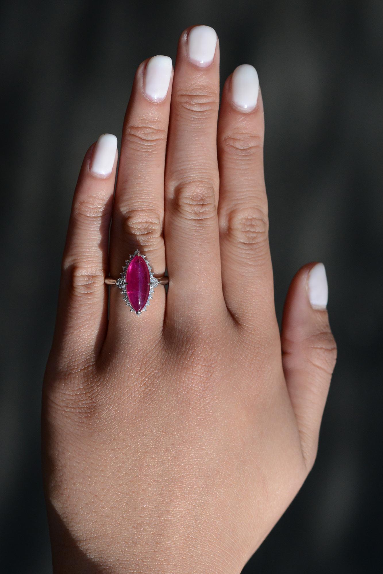 This bold cocktail ring highlights a remarkable elongated ruby cabochon. The glowing marquise shape ruby emits a passionate, luminous red and is surrounded with a halo of 20 round diamonds that give an alluring twinkle. Paired with a platinum band