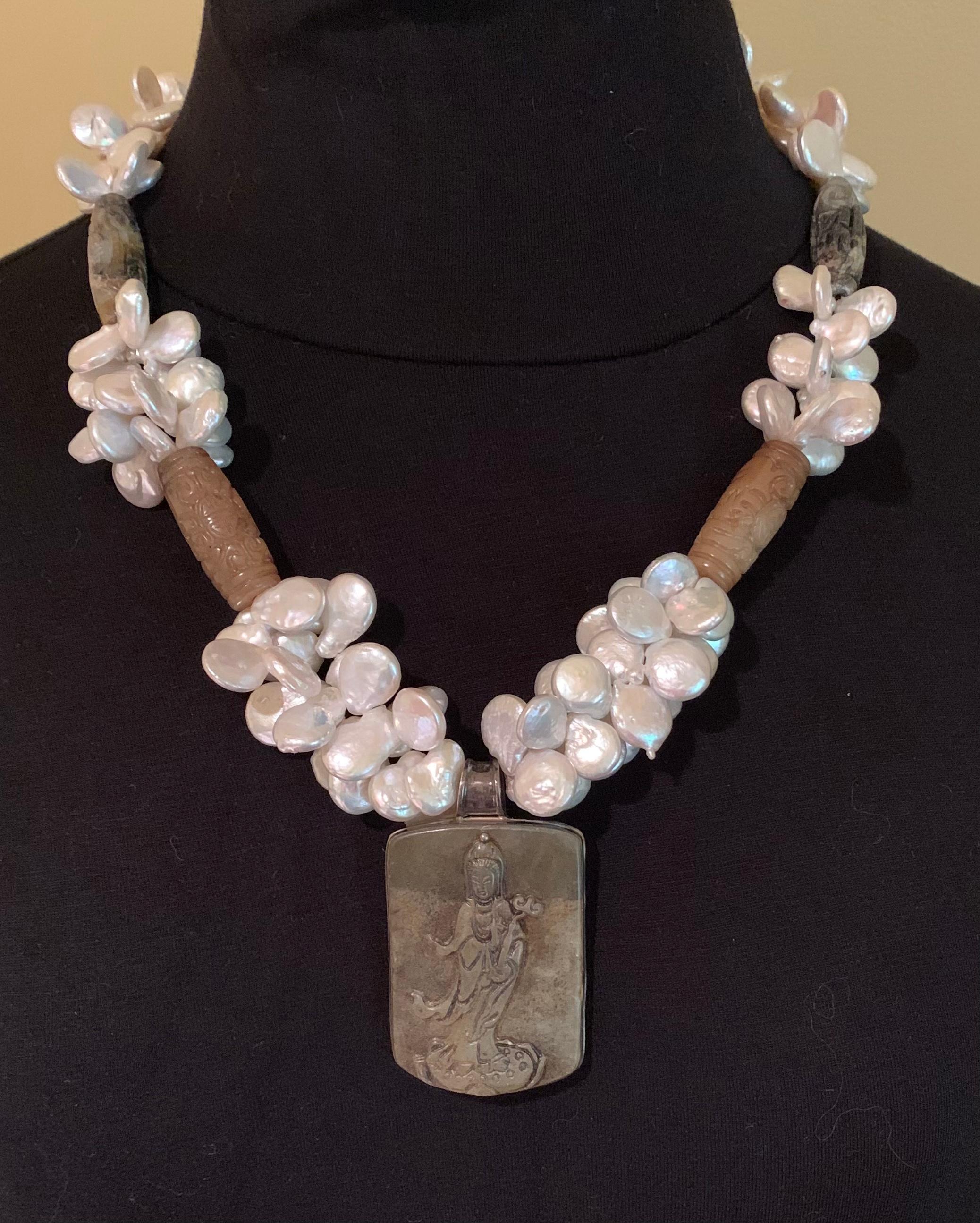 Estate A. Jeschel Asian motif jade, Keshi pearl and tiger's eye statement necklace.
The central jade pendant depicting Guan Yin, the Goddess of compassion and wisdom, with a profusion of beautiful Keshi pearls in cloud-like formations above, joined