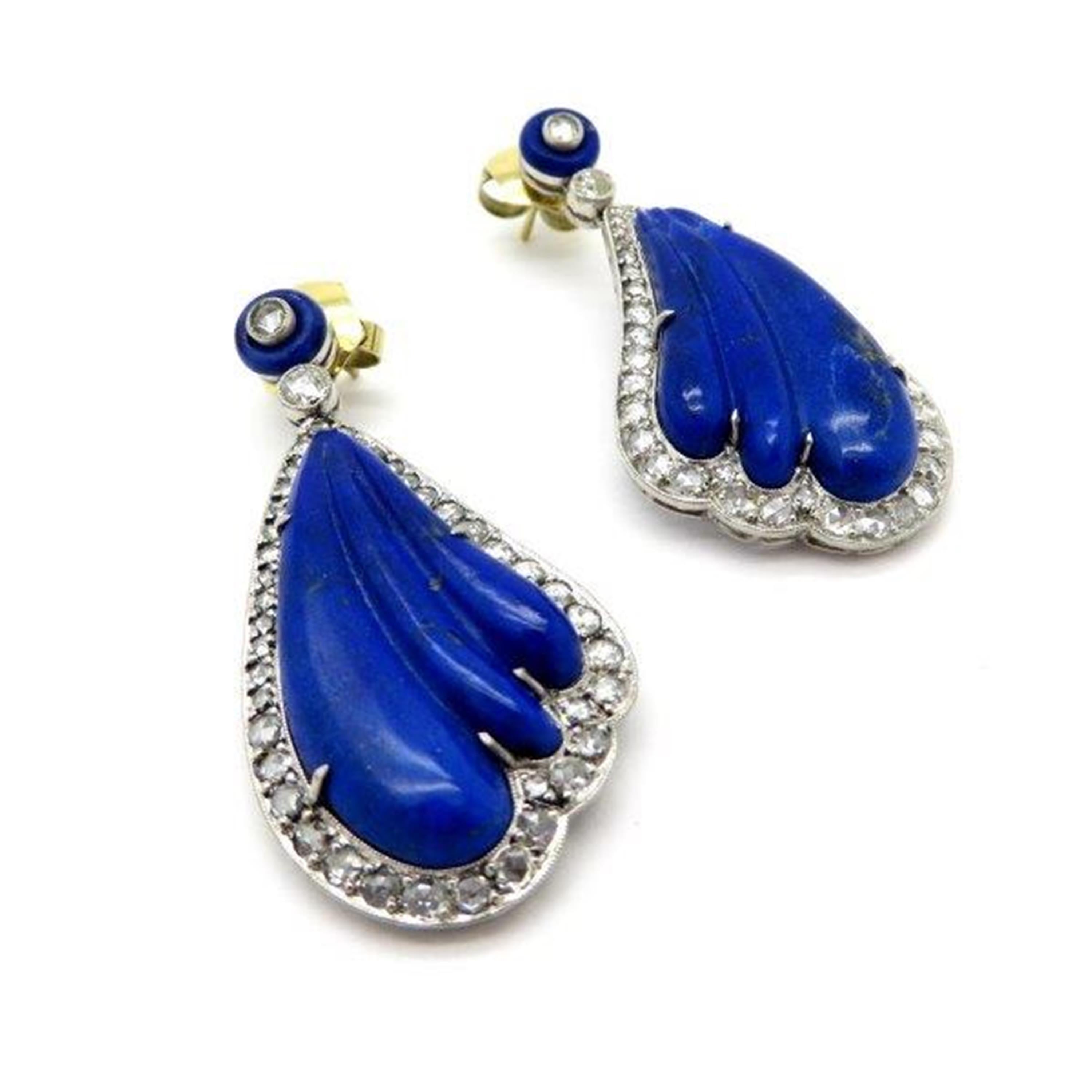 Estate platinum lapis lazuli and diamond dangle earrings.  Displaying two fine quality scalloped carved lapis lazuli gemstones weighing a combined total of 25.16 carats. Accented with 86 rose cut diamonds, with various measurements, weighing a