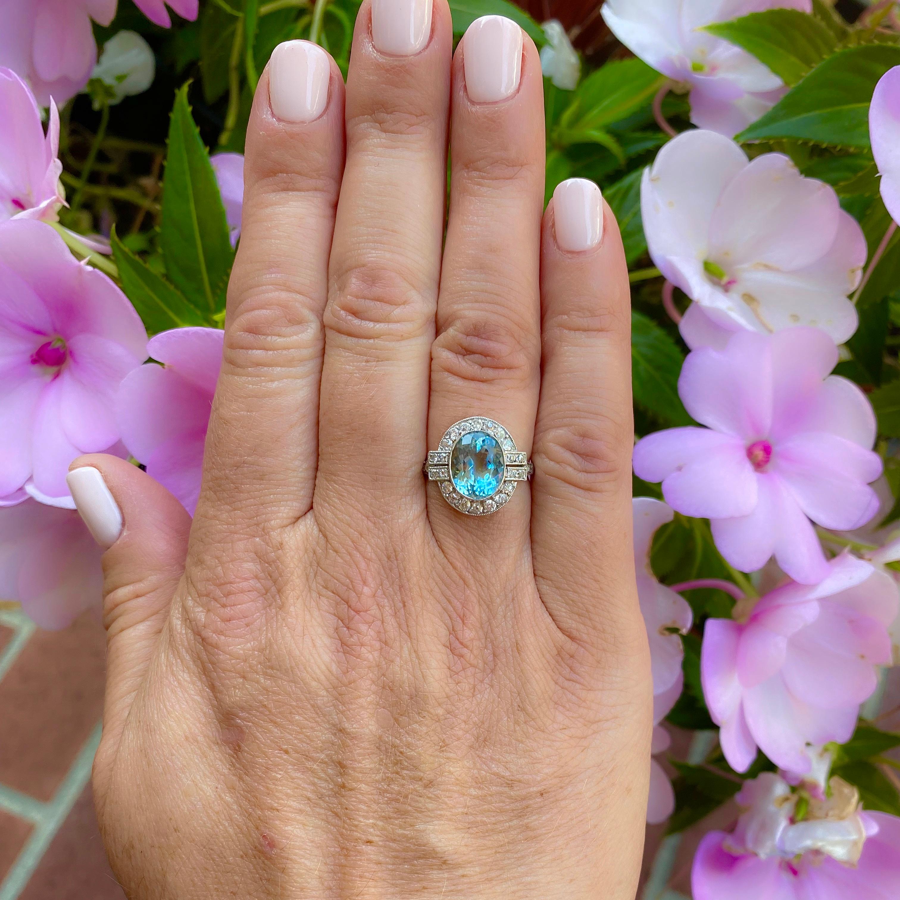 Classic period glamour! The platinum ring centers a bezel-set oval shaped aquamarine weighing 2.66 carats, with the surround and shoulders set with 28 old European-cut diamonds, weighing in total an estimated 0.45-ct. The ring weighs 3.9 grams, and