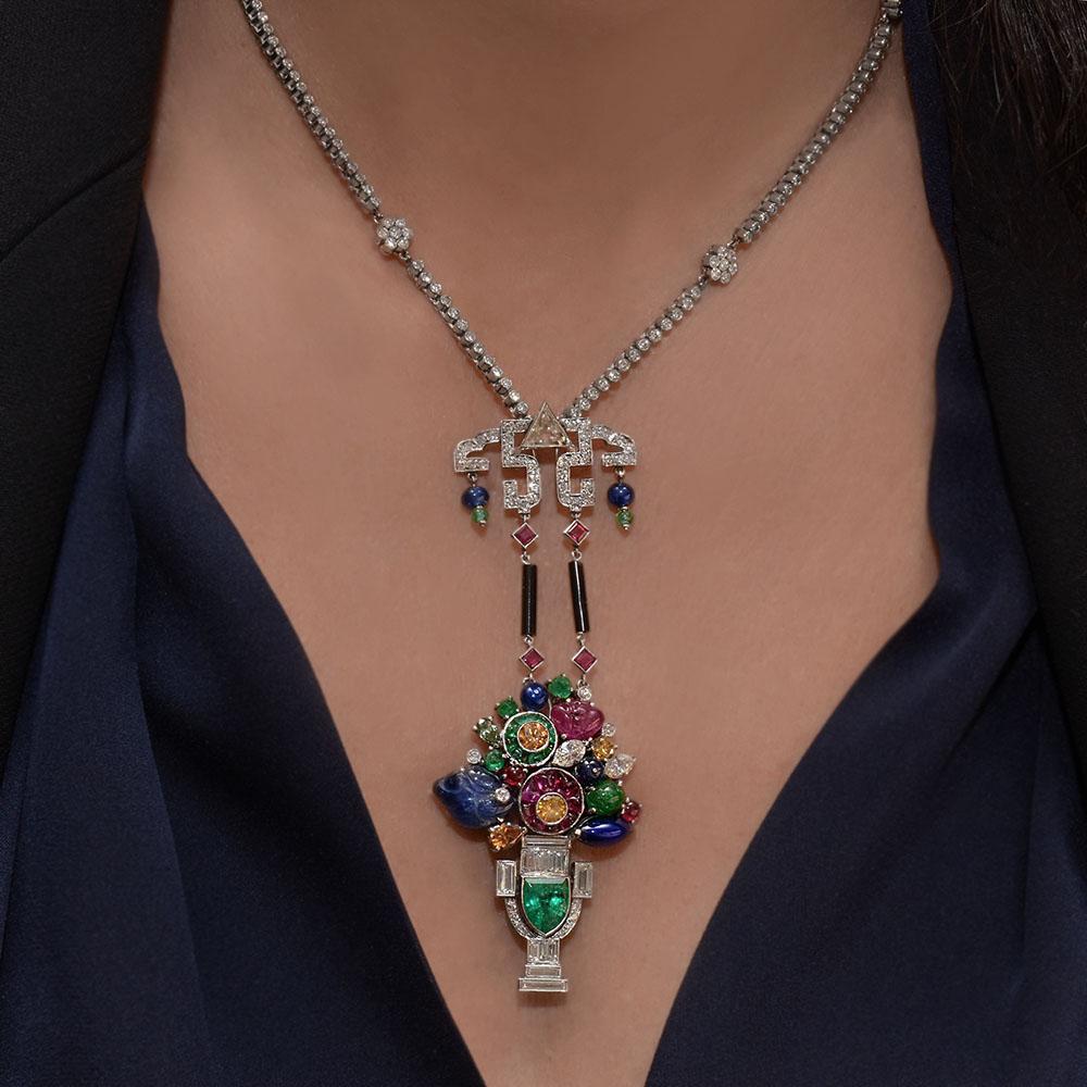 This stunning estate piece is Designed in the art deco Tutti Frutti style. This pendant necklace composed of round brilliant diamonds hand set in Platinum with a Art Deco Tutti Frutti style basket composed of hand carved Rubies, Sapphires and