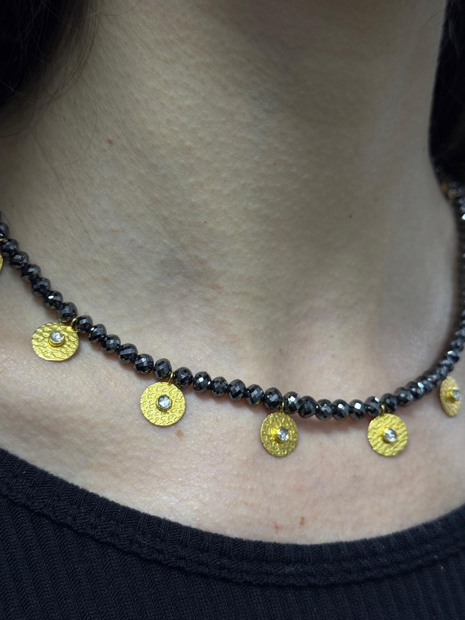 Bold and modern, this estate necklace features a strand of shimmering black diamond beads paired with 11 yellow gold disc charms centered by sweet rose cuts with for a dynamic, eye-catching design. At 16 inches and 24.7 grams, it’s lightweight yet