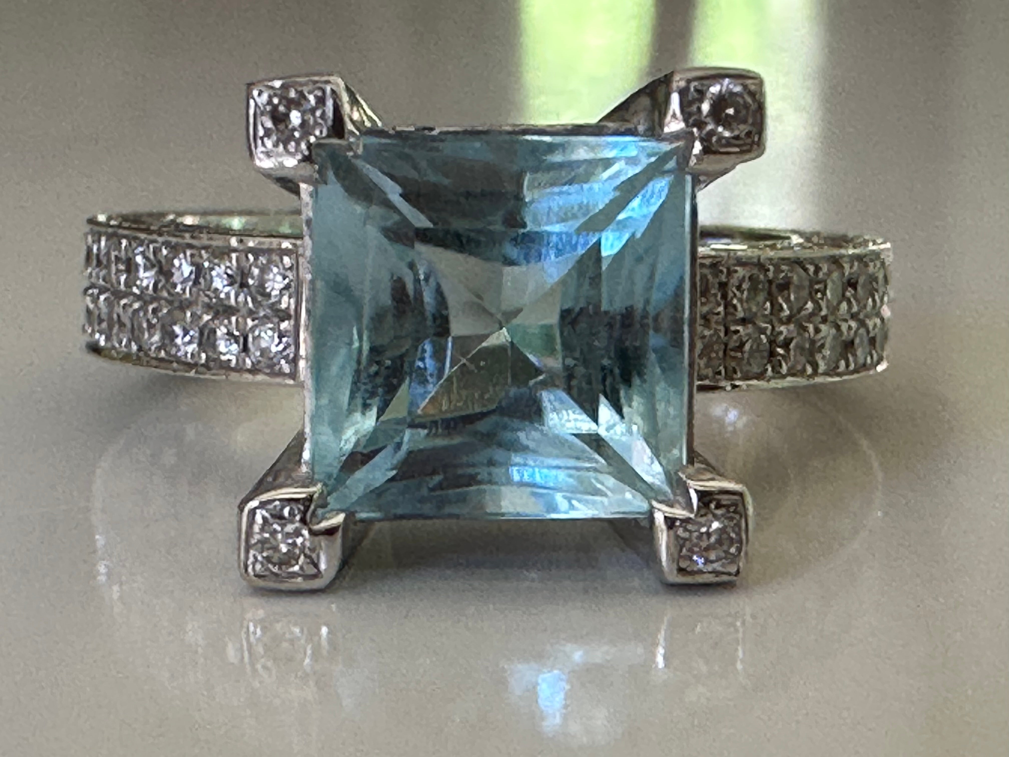 This gorgeous Estate cocktail ring is designed around a large, square cut clear blue topaz center stone measuring 8.35x8.4mm. The 18k white gold band is inlaid (on both the top and the sides of the band) with 186 shimmering round brilliant-cut
