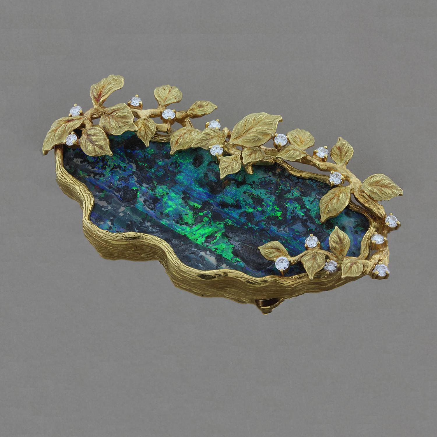 A fascinating boulder opal full of life and gleam in a pond-like setting surrounded by diamond studded tree branches. The 1.06 carats of round cut diamonds are spread about the leaves in this 18K yellow gold brooch. With the two bails on the back of