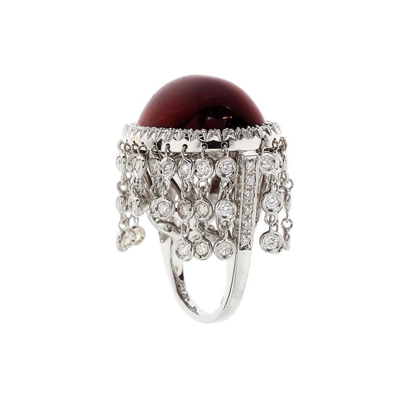 This one of a kind estate ring features a deep vivid red rubelite tourmaline weighting approximately 31 carats. The tourmaline is haloed and accented by 2.42 carats VS quality round cut diamonds. The chandelier style halo of bezel set diamonds