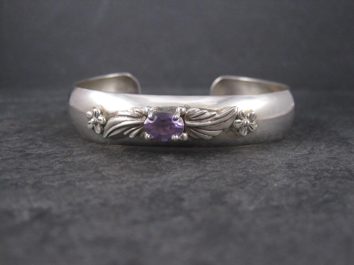 This gorgeous 1987 cuff bracelet is the creation of Carol Felley.
It is sterling silver and features a 6x8mm amethyst gemstone.

At its widest point, this bracelet measures 9/16 of an inch.
It has an inner circumference of 6 1/4 inches, including