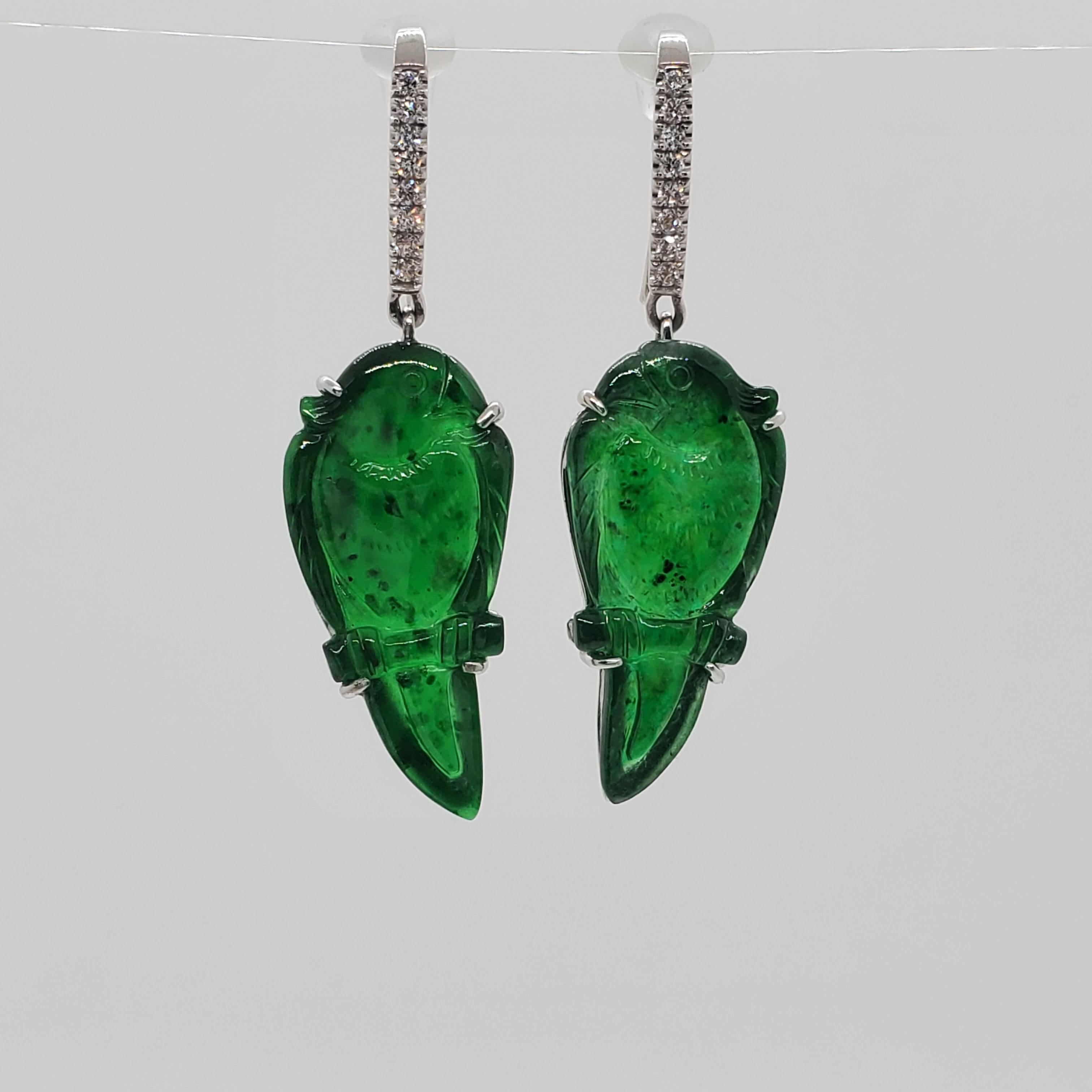Stunning carved green jade parrots with a beautiful deep green color.  Good quality, white and bright diamond rounds weighing 0.15 ct.  Handmade dangle earrings in platinum.  These earrings are unique and would work for day or night wear.  Excellent