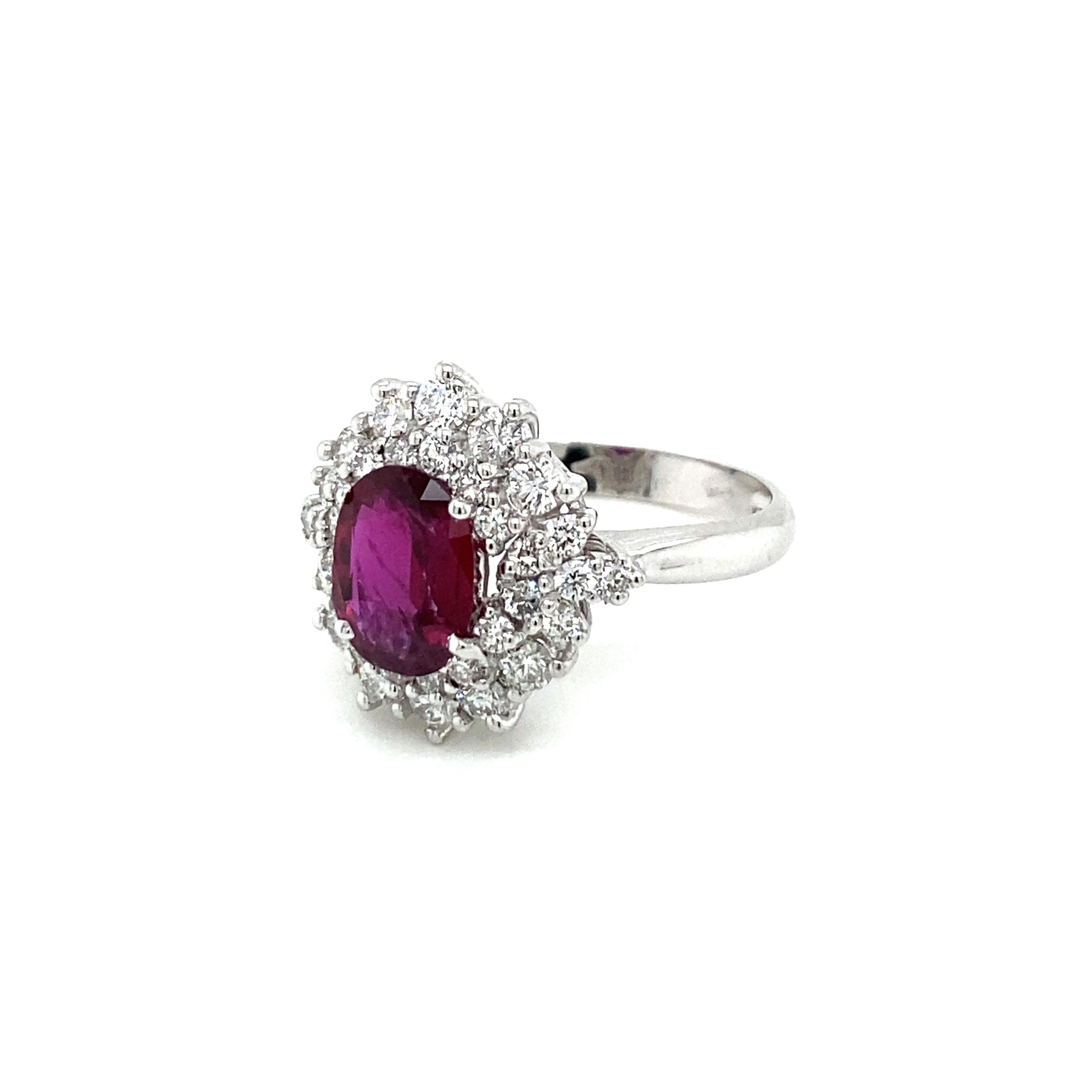 Classy and timeless, this beautiful 18k white Gold cluster ring features a 1.94 Carat oval-cut Ruby, origin Thailand, with a vibrant and rich purplish red color flanked by a double halo composed of sparkling Round Brilliant cut Diamonds for a total
