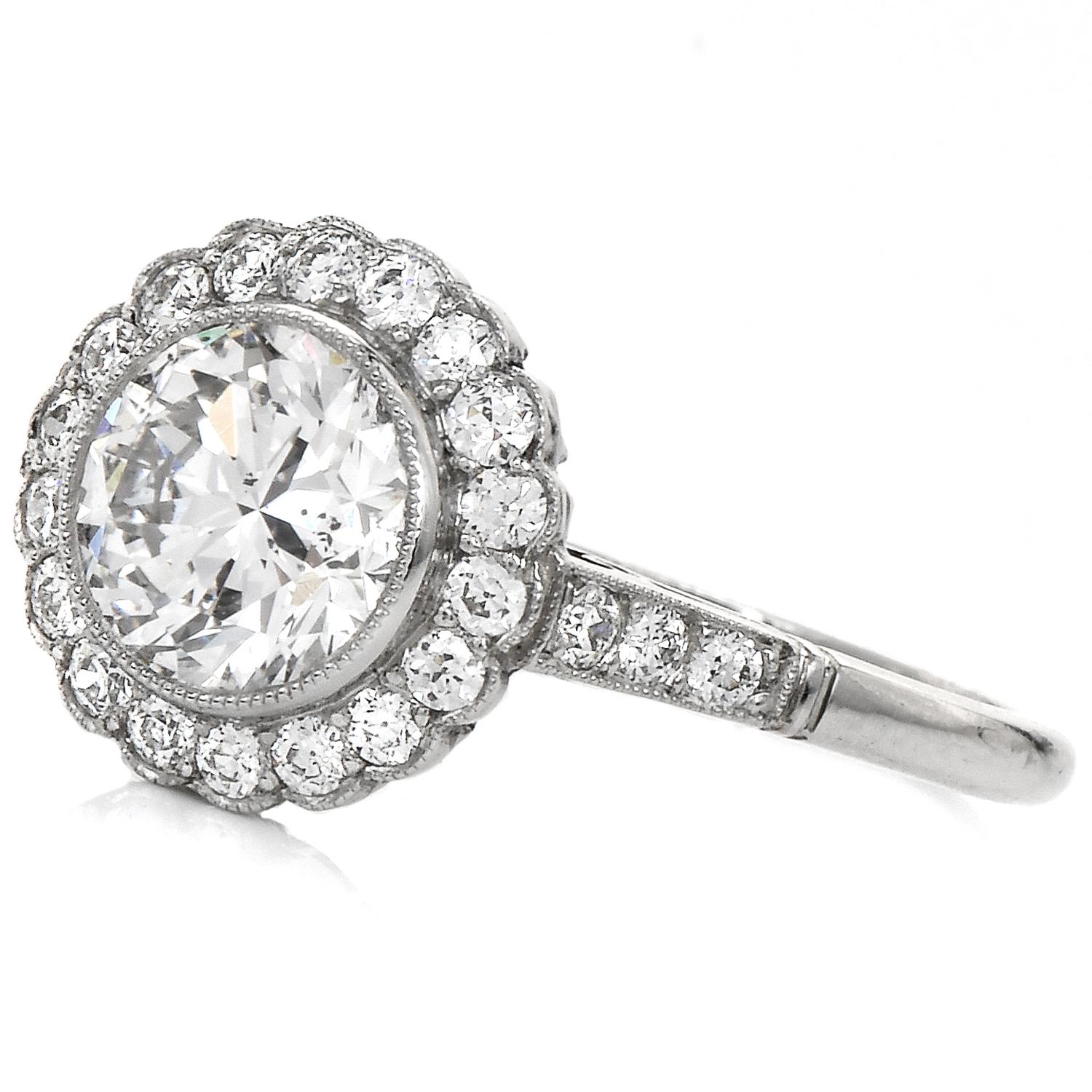 A romantic and classic Halo Engagement Ring.

Crafted in solid Platinum, the center is adorned by a Genuine Diamond, a RoundCut, Bezel Set, 1.26 carats, F-G color & SI2 clarity.

Complimenting the sparkly halo and shank are round cut, Prong-set,