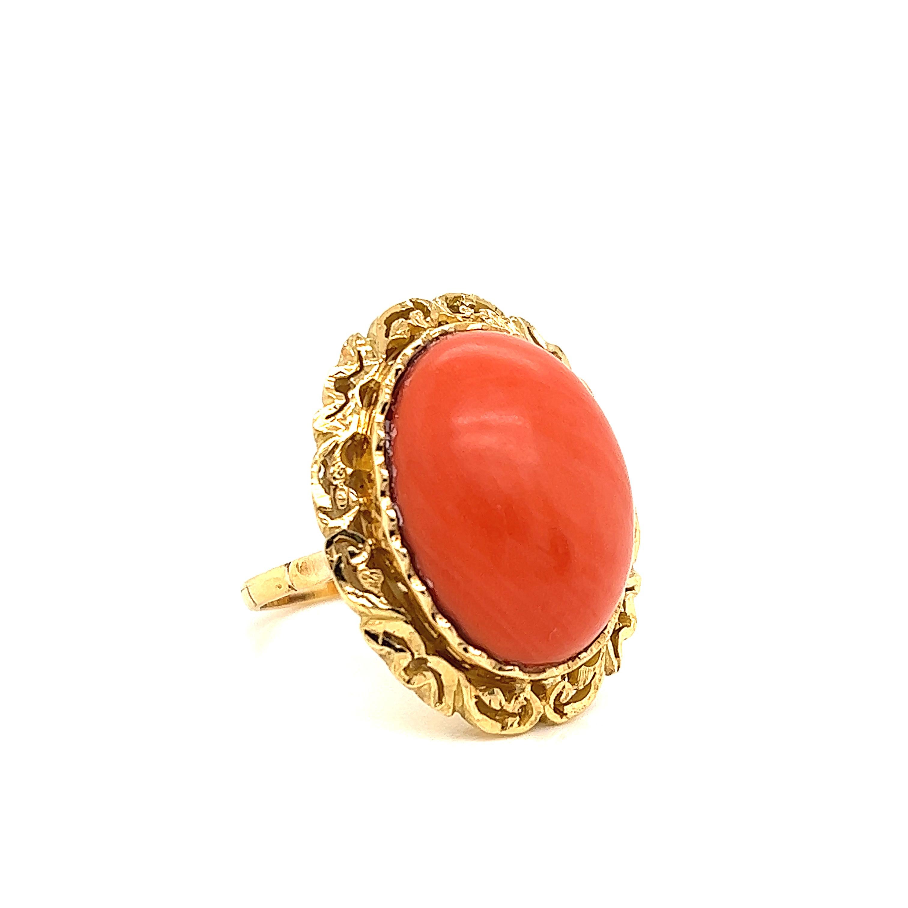 Gorgeous ring crafted in 18k yellow gold. The ring shows exquisite detail as a large coral gemstone is the focal point. The coral shows a beautiful red color and highlights this one of a kind design. The gemstone is bezel set and has a detailed