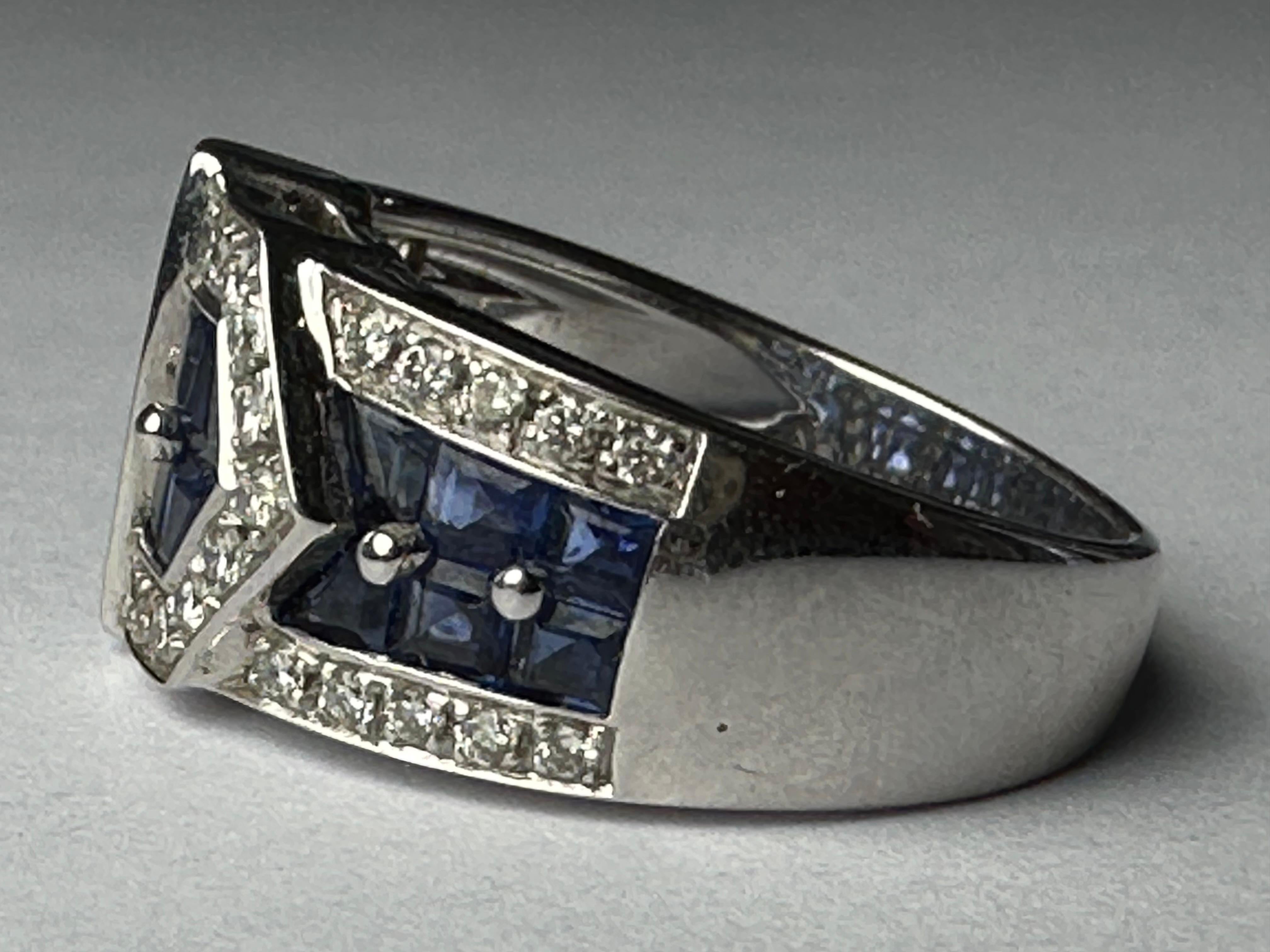 Thirty-seven round brilliant-cut diamonds totaling approximately 1.00 carat, FG color, VS clarity and sixteen royal blue square-cut sapphires adorn this showstopper Estate buckle ring. Set in 18K white gold. 
