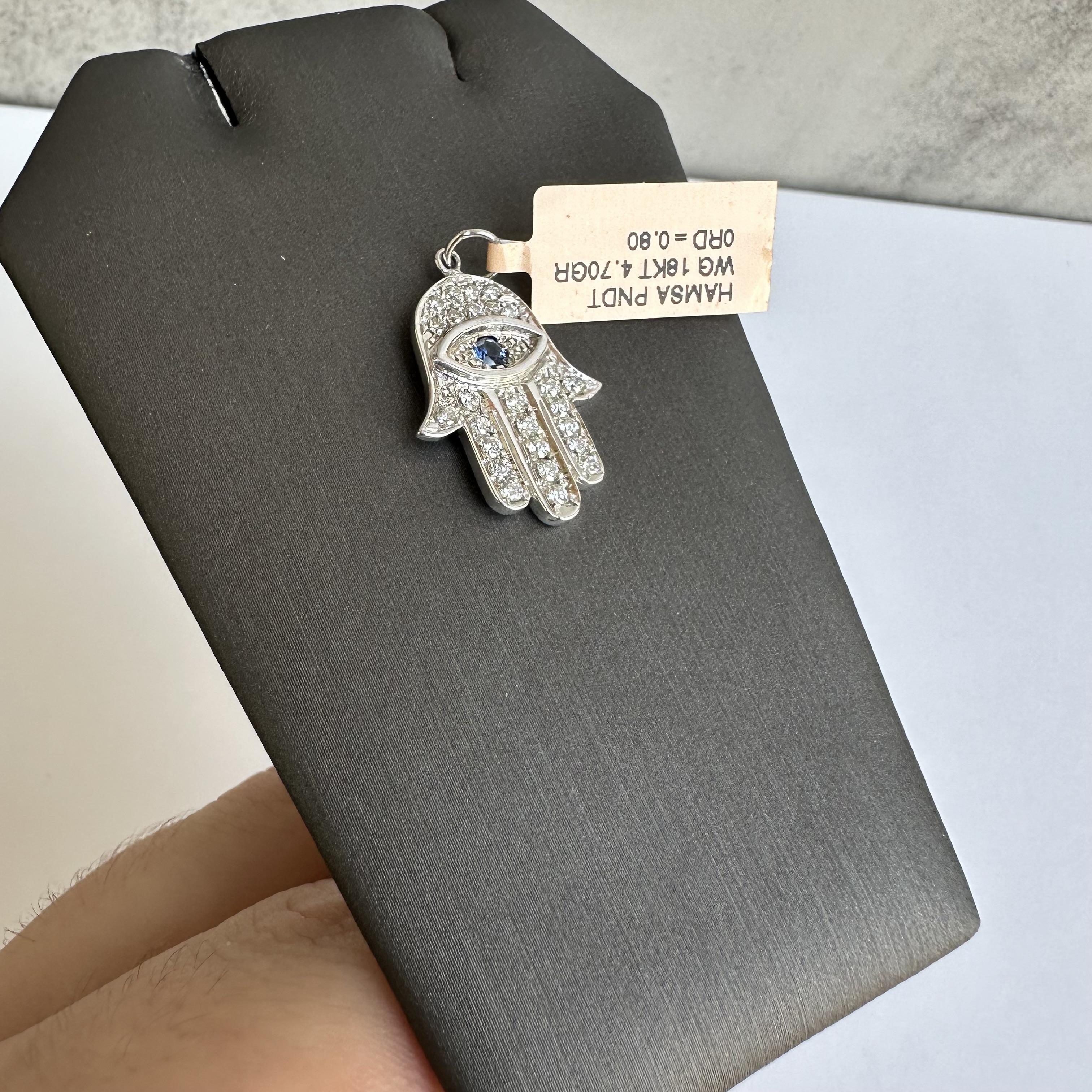 Embrace the beauty and symbolism of the Estate Diamond and Sapphire Hamsa Pendant in 18kt White Gold. This exquisite piece features a stunning combination of diamonds and sapphire, making it a timeless addition to any jewelry collection.
Design and