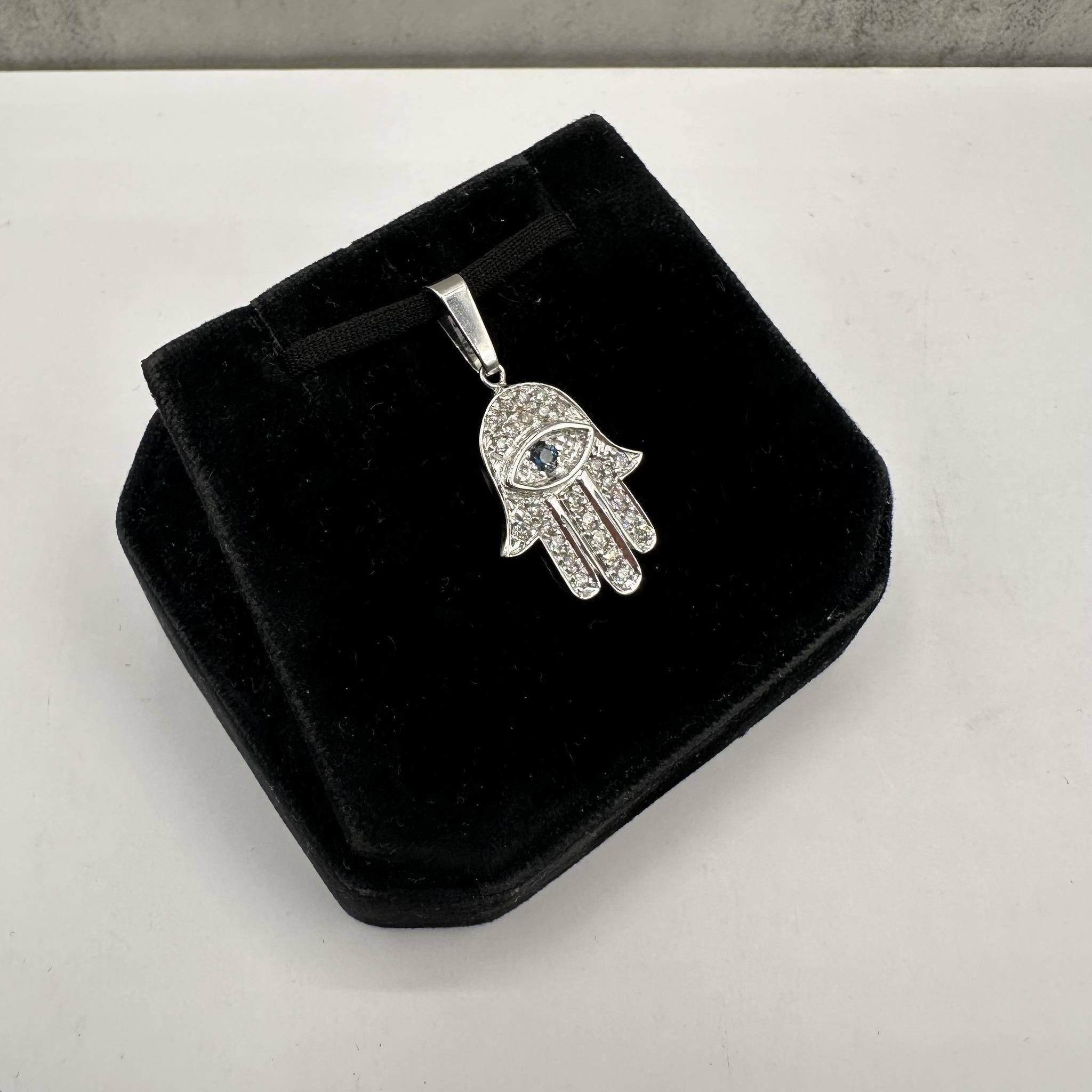 This stunning Estate Diamond and Sapphire Hamsa Pendant is set in 18kt White Gold, exuding both elegance and symbolism. It features approximately 0.80ctw of HI VS diamonds, providing a brilliant, eye-catching sparkle. Complementing the diamonds are