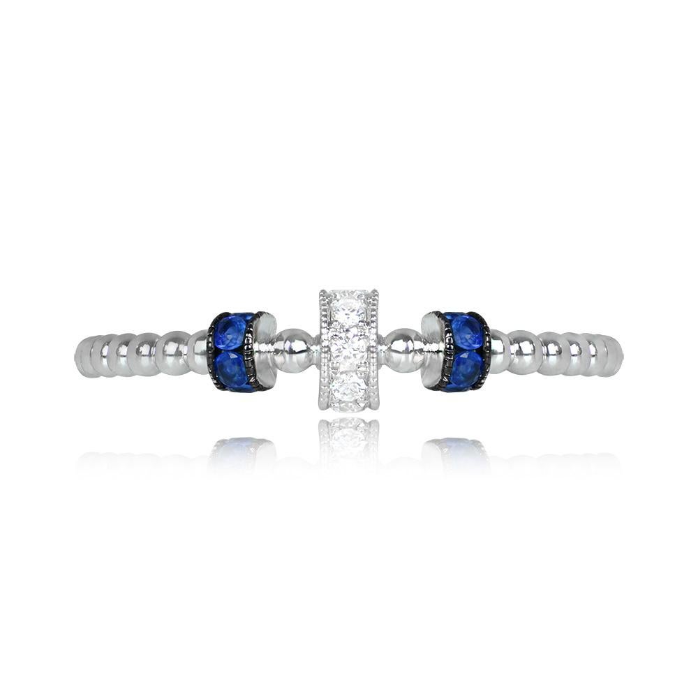 A stylish band with rows of round brilliant cut diamonds and round cut sapphires set in rolled portions. The total diamond weight is approximately 0.03 carats, and the total sapphire weight is around 0.11 carats. Handcrafted in 18k white gold, this