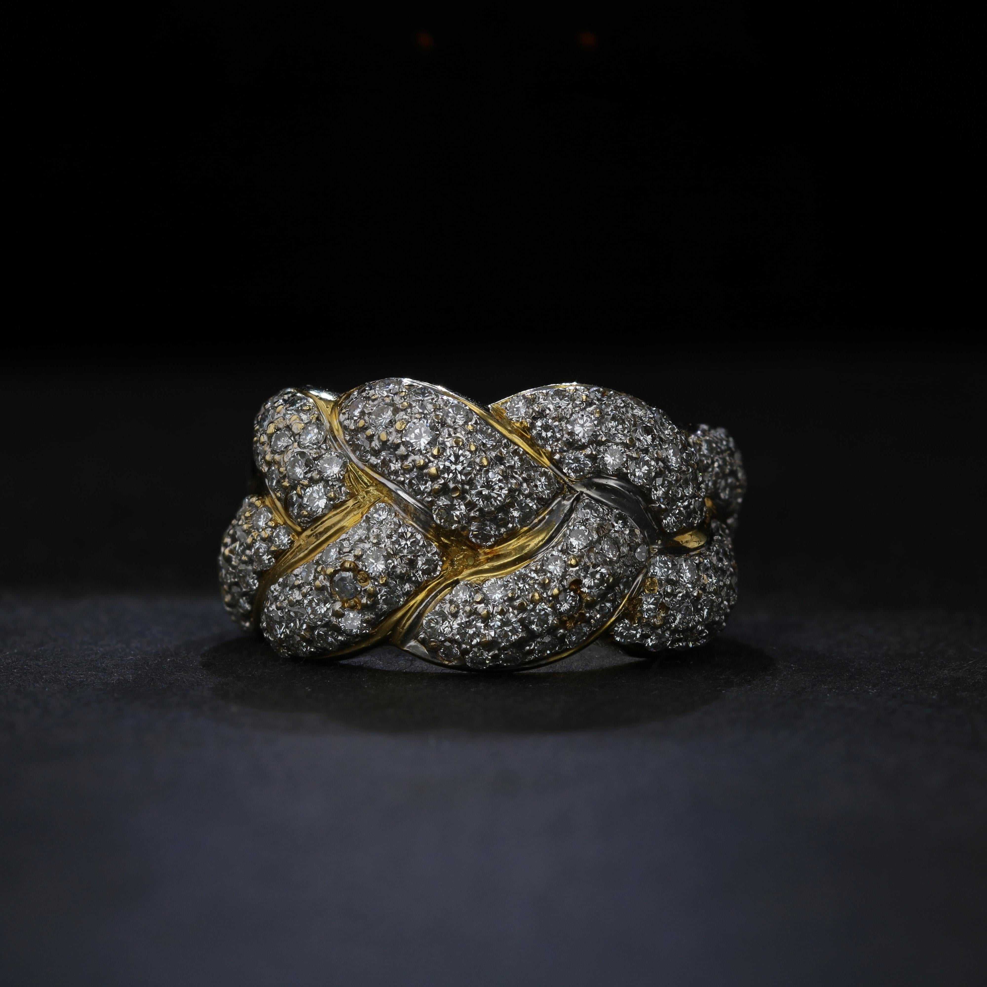 18K white and yellow gold come together in a braid motif to envelop approximately 143 pave set round brilliant diamonds in this retro ring. The diamonds together weigh approximately 2.50 carats and have average color of J and average clarity of SI2. 