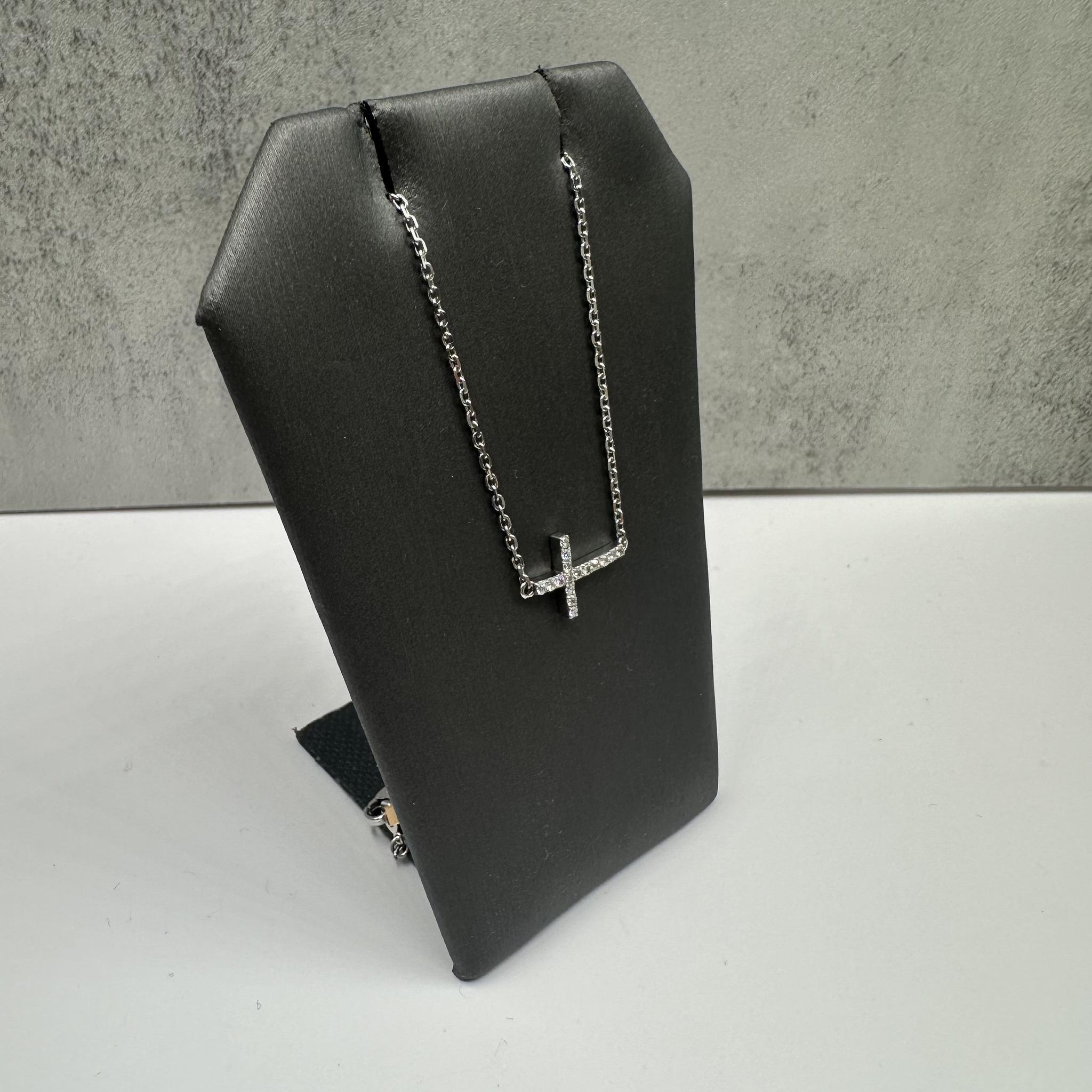 This elegant Estate Diamond Sideways Cross Necklace in 14kt white gold features approximately 0.16ctw of natural GH SI2-I1 round diamonds, adding a subtle sparkle to the sideways cross design. The length is adjustable between 12 and 14 inches,