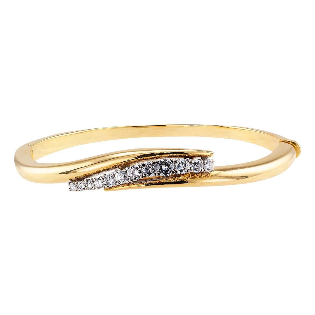 Estate diamond and yellow gold hinged bangle bracelet circa 1980.

DETAILS:

DIAMONDS: twelve round brilliant-cut diamonds totaling approximately 0.65 carat, approximately G - H color, VS clarity.

METAL: 18-karat yellow gold.

MEASUREMENTS: