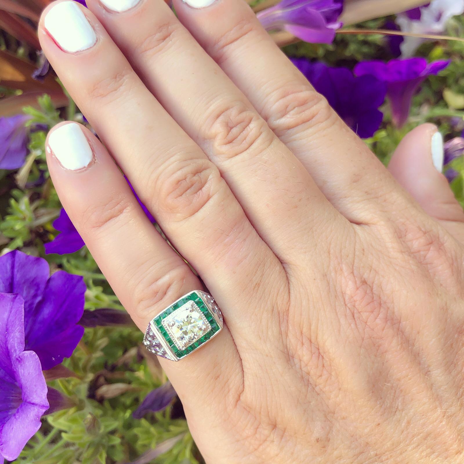 With vintage flair, this 18k white gold square halo ring is unique and wearable. Centering a 1.01 carat round brilliant-cut diamond, framed within a halo of 22 square-cut emeralds, with wide pierced shoulders which add a delicate, lacy look. The
