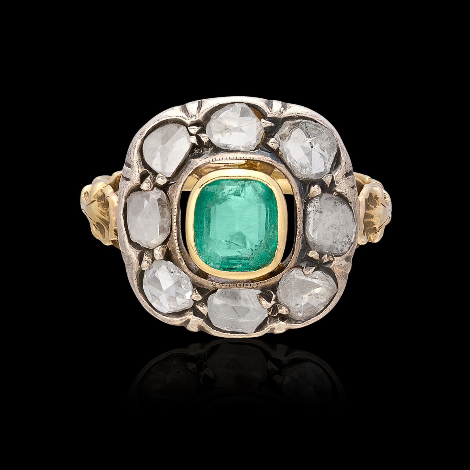 A gorgeous piece of history at your fingertips. This incredible antique emerald ring circa 1840 features a well saturated 0.55 carat emerald surrounded by a halo of 8 old single cut stones for 0.80 carats. The silver topped 18 karat yellow gold ring