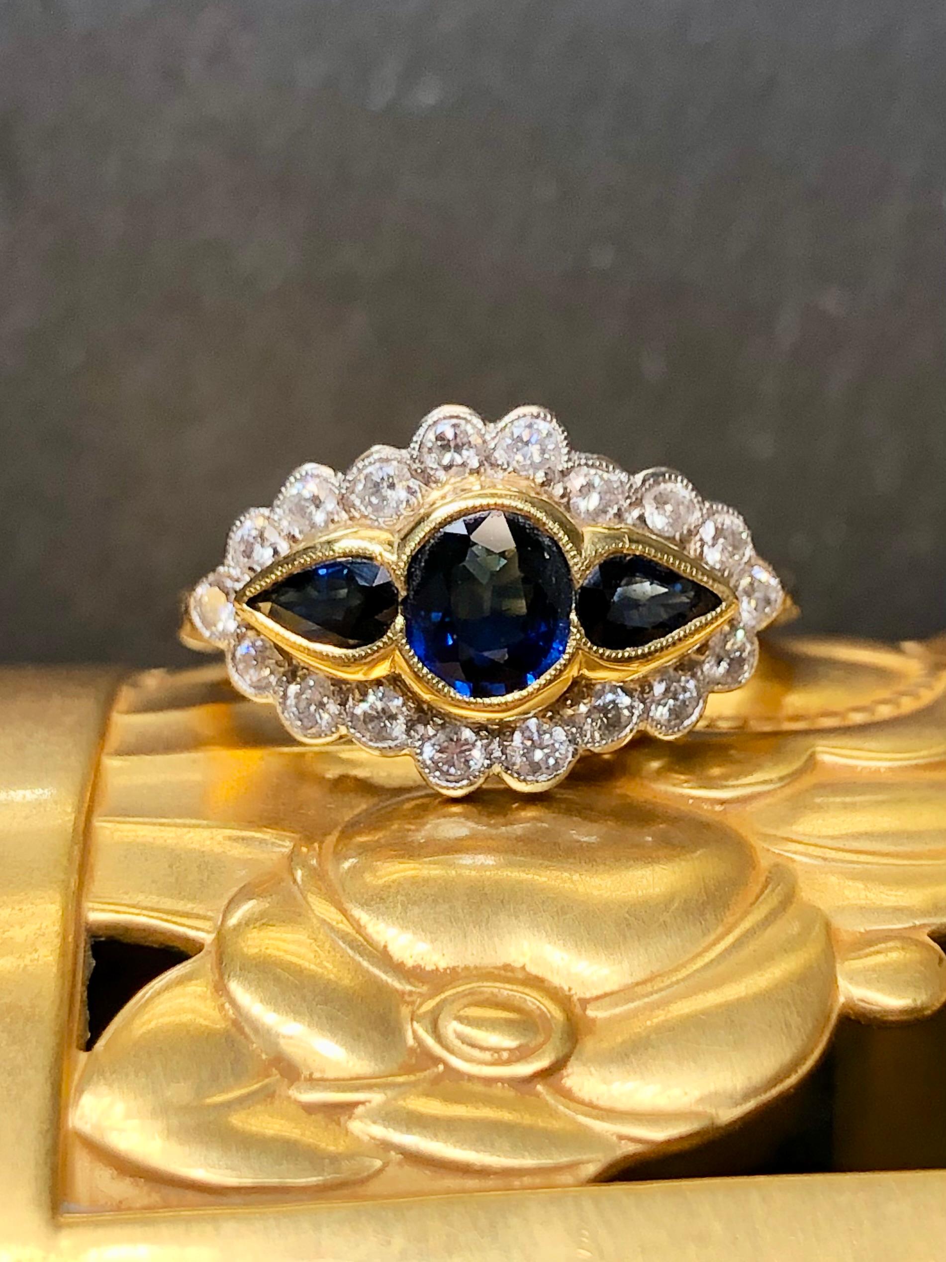 
A finely made 3 stone sapphire and diamond ring crafted in 18K yellow gold topped in platinum. It has been set with three central oval and pear shaped natural sapphires weighing approximately 1.15cttw surrounded by approximately .54cttw in well