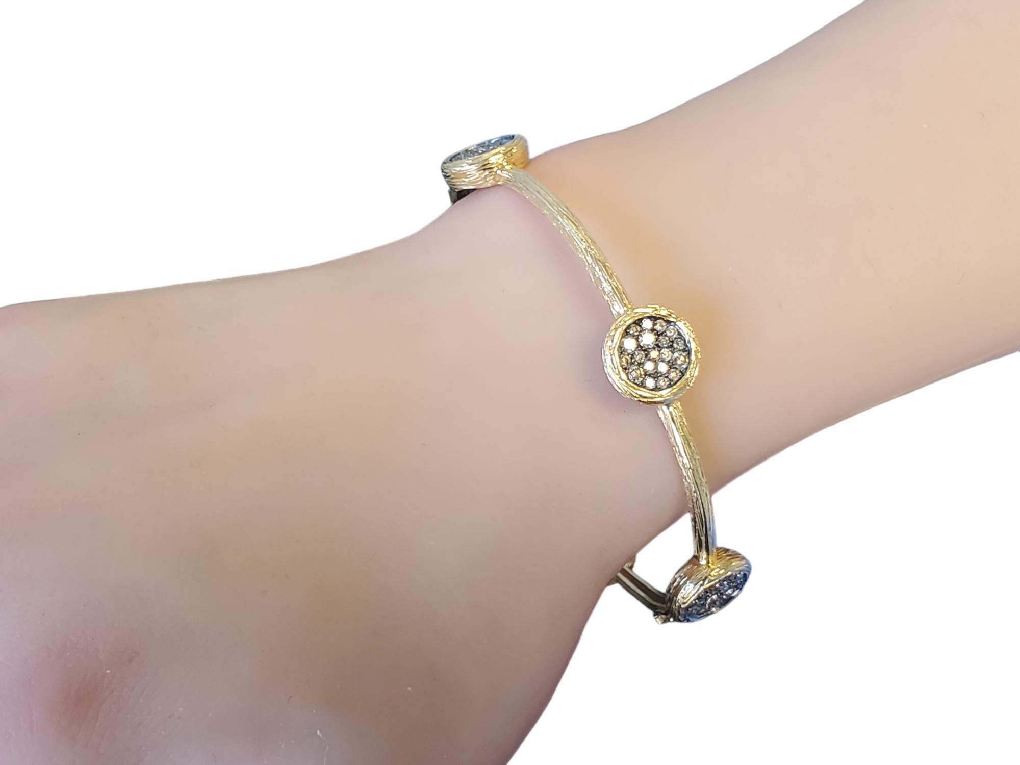 Listed is a 14k yellow gold bangle with nice mixed shade chocolate color diamonds. This designer bracelet has a really nice and unique finish to the metal, the craftsmanship is outstanding. It features 1.59tcw round brilliant diamonds that are SI in