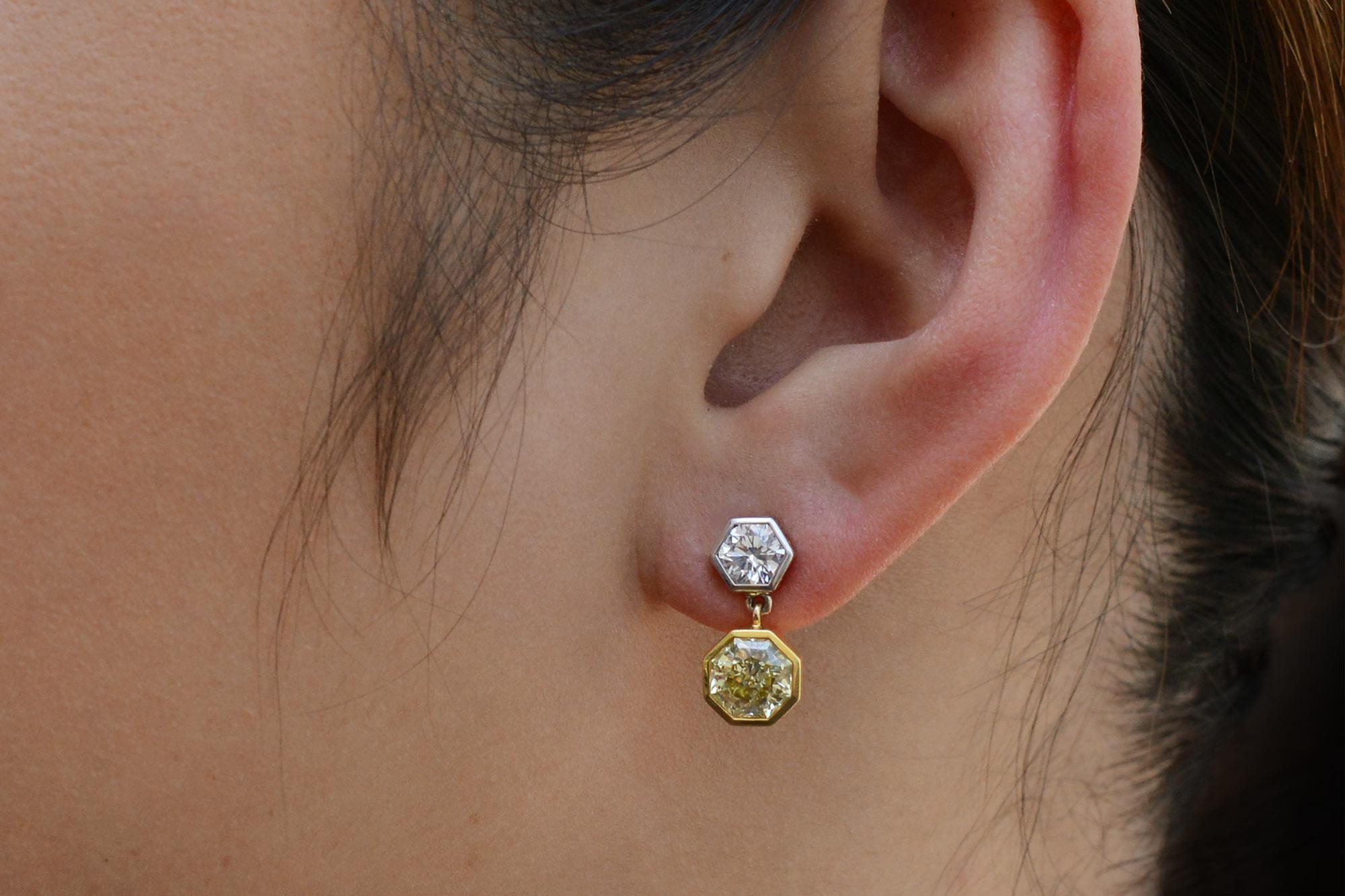 This contrastive pair of earrings is truly phenomenal. Topped with an icy round brilliant cut diamond that are each accompanied by a Gemological Institute of America report. Dangling below that is a striking yellow diamond complimented with 18k