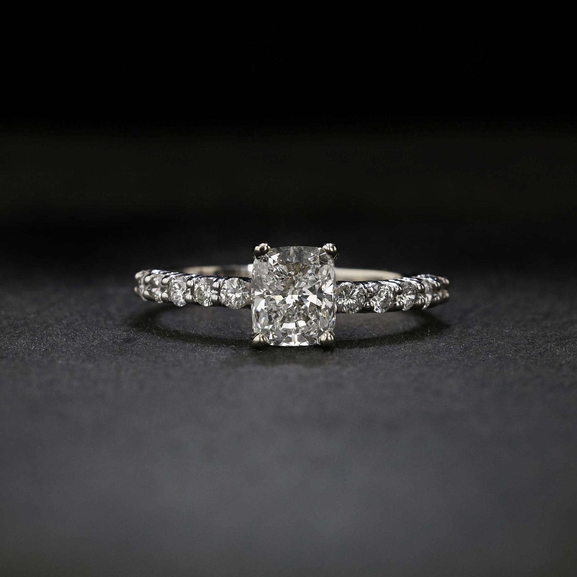 A GIA certified cushion-cut diamond of 1.22 carats, G color, and VS1 clarity is accentuated by a sparkling diamond shank. The diamonds adorning the shank are round and of matching color and clarity to the center stone. Fashioned in platinum.