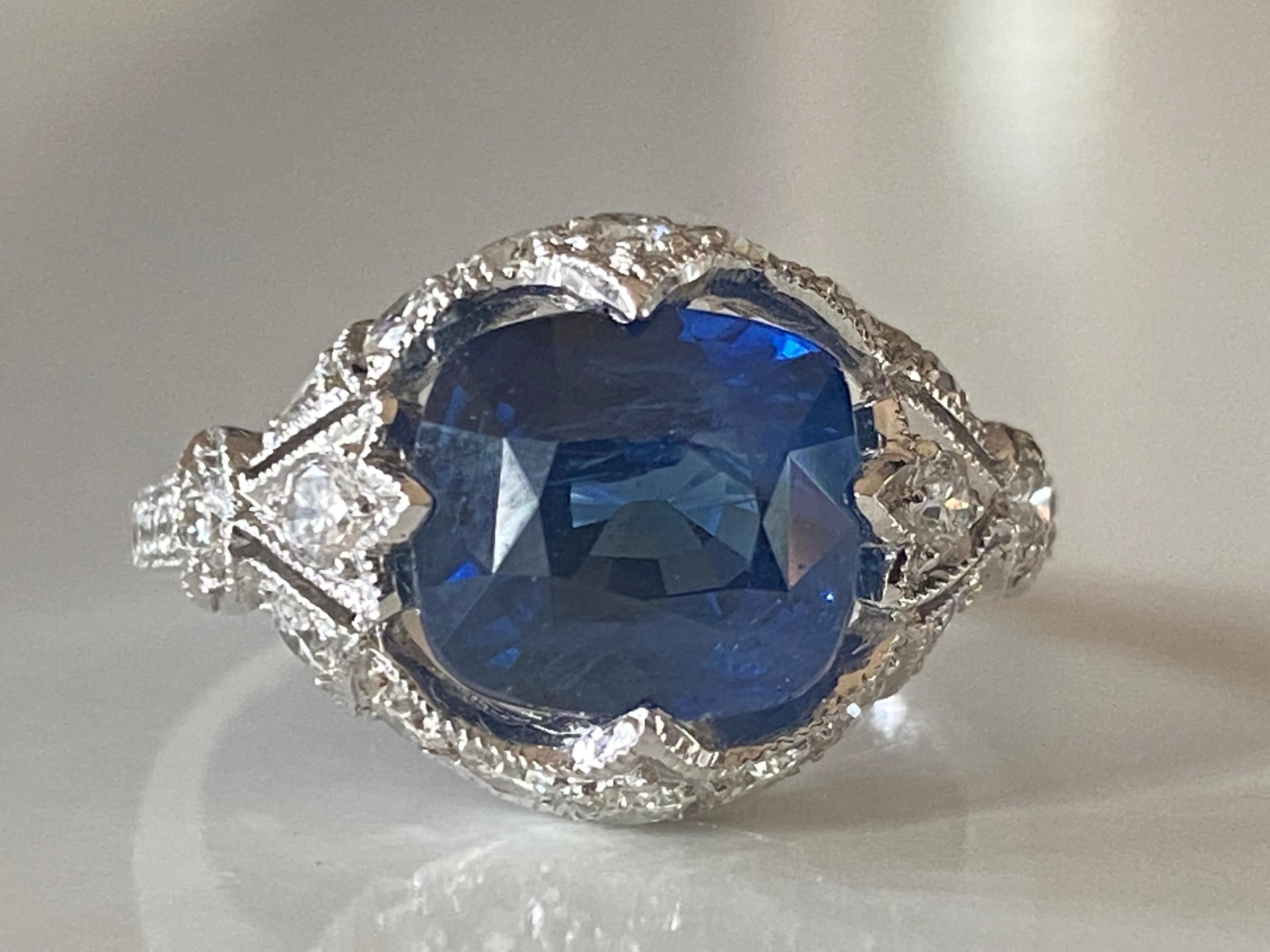 This stunning Estate gem features a cushion cut Sri Lankan natural blue sapphire measuring approximately 3.89 carats and adorned with 26 round-brilliant diamonds totaling approximately 1.00 carat set in 18kt white gold.
